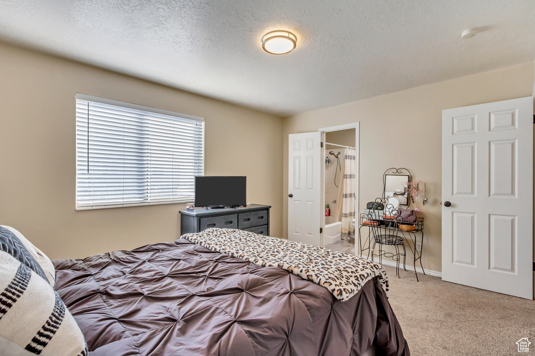 Carpeted bedroom featuring ensuite bathroom and a textured ceiling