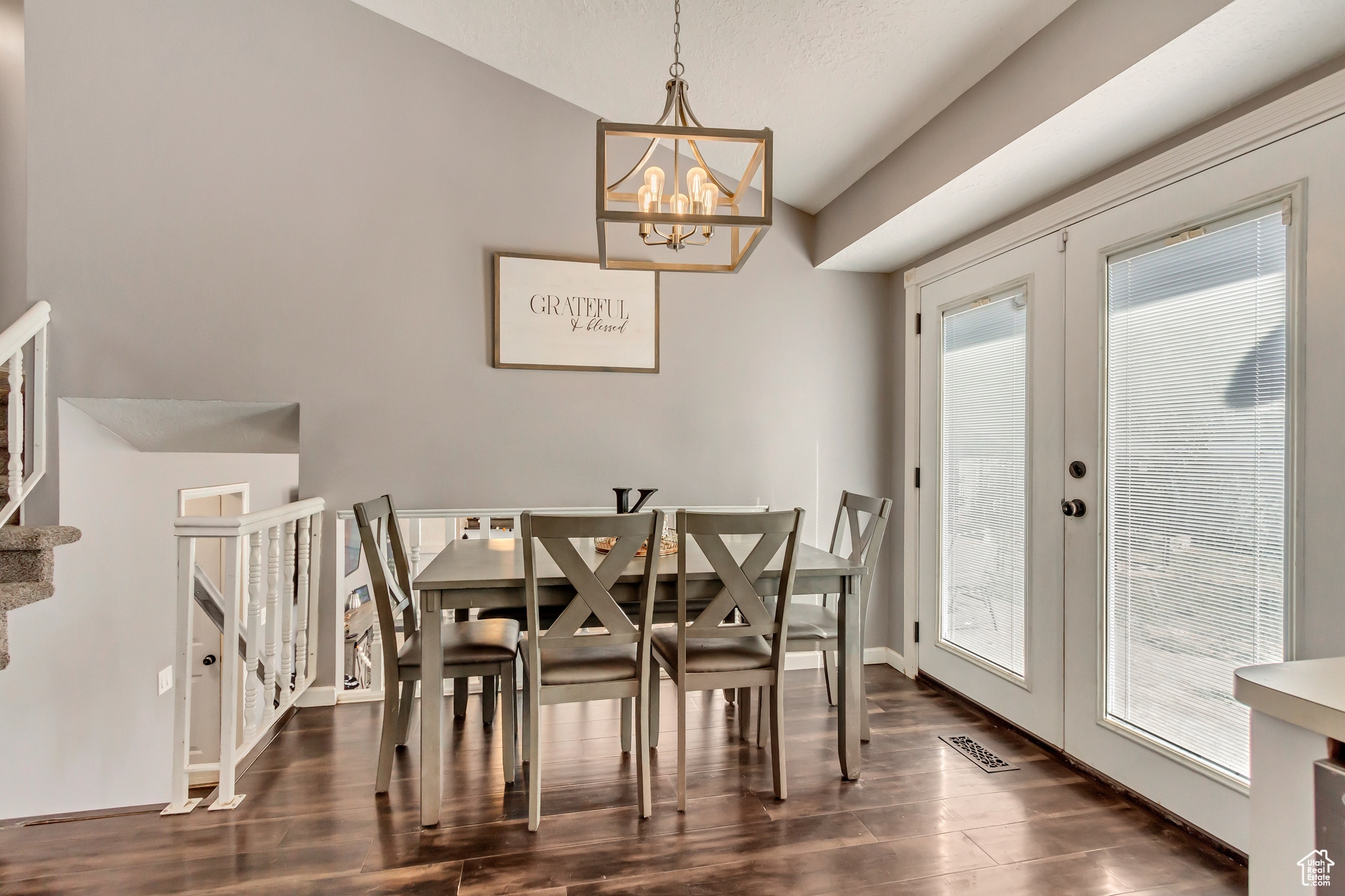 Dining space featuring dark wood-type flooring, french doors, a chandelier, and plenty of natural light