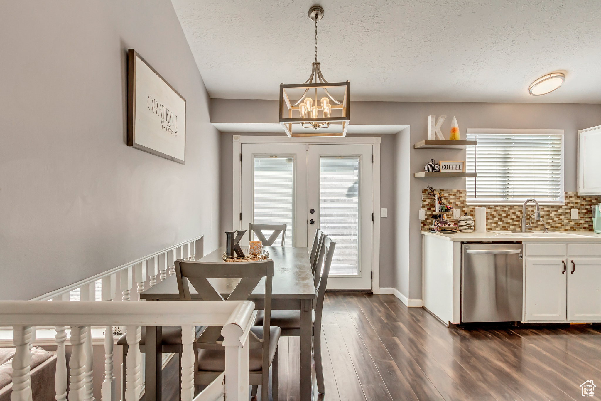 Dining room with french doors, a healthy amount of sunlight, a textured ceiling, and an inviting chandelier