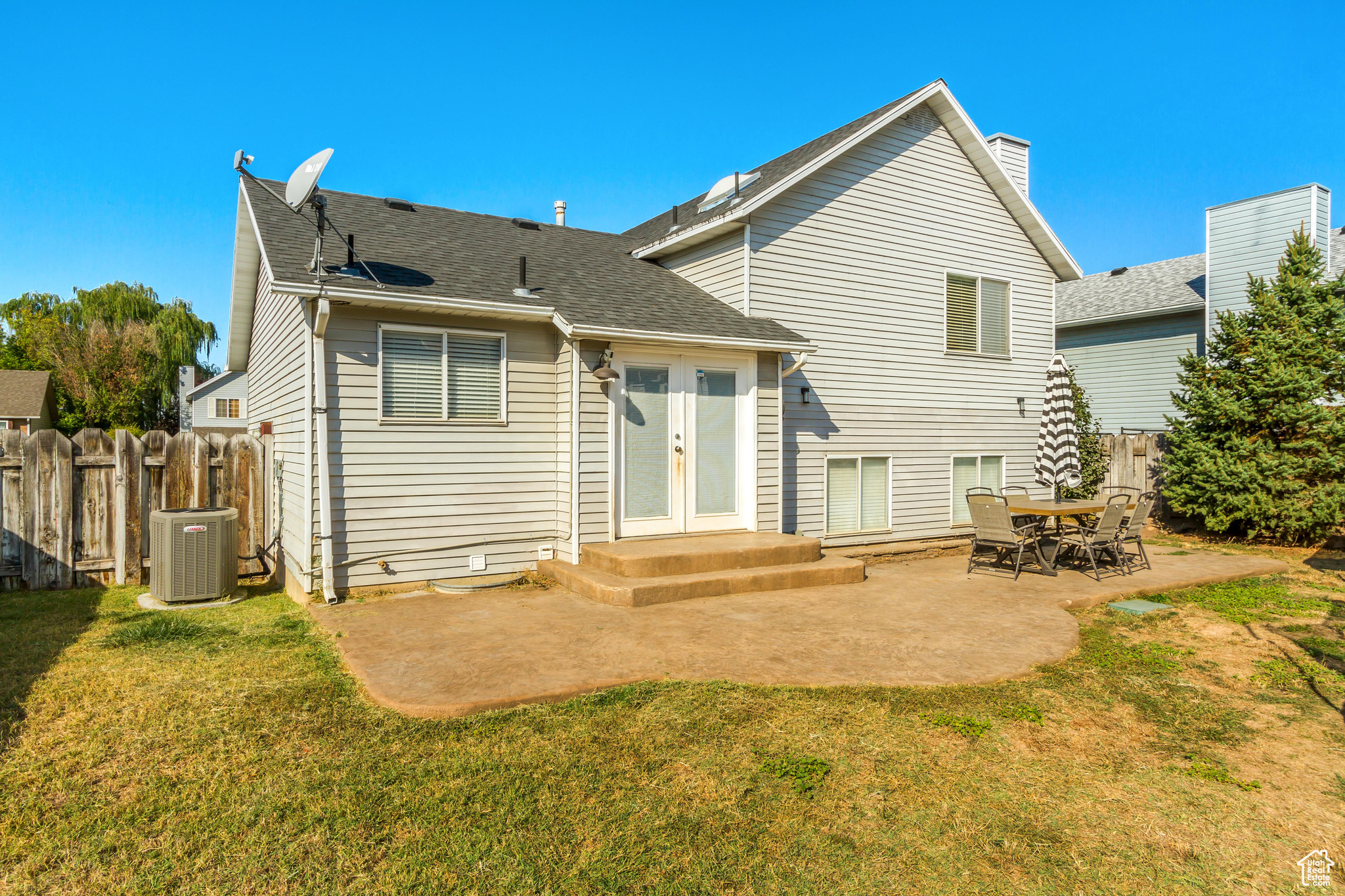 Back of property with central AC unit, a patio area, a yard, and french doors