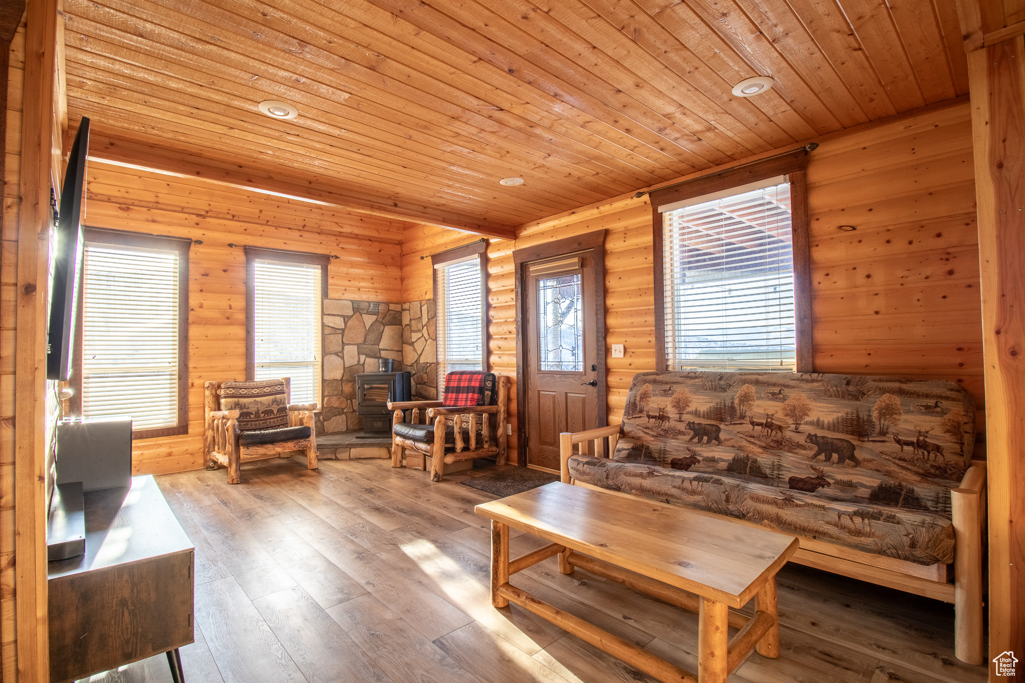 Living room with hardwood / wood-style floors, a wood stove, rustic walls, and wooden ceiling