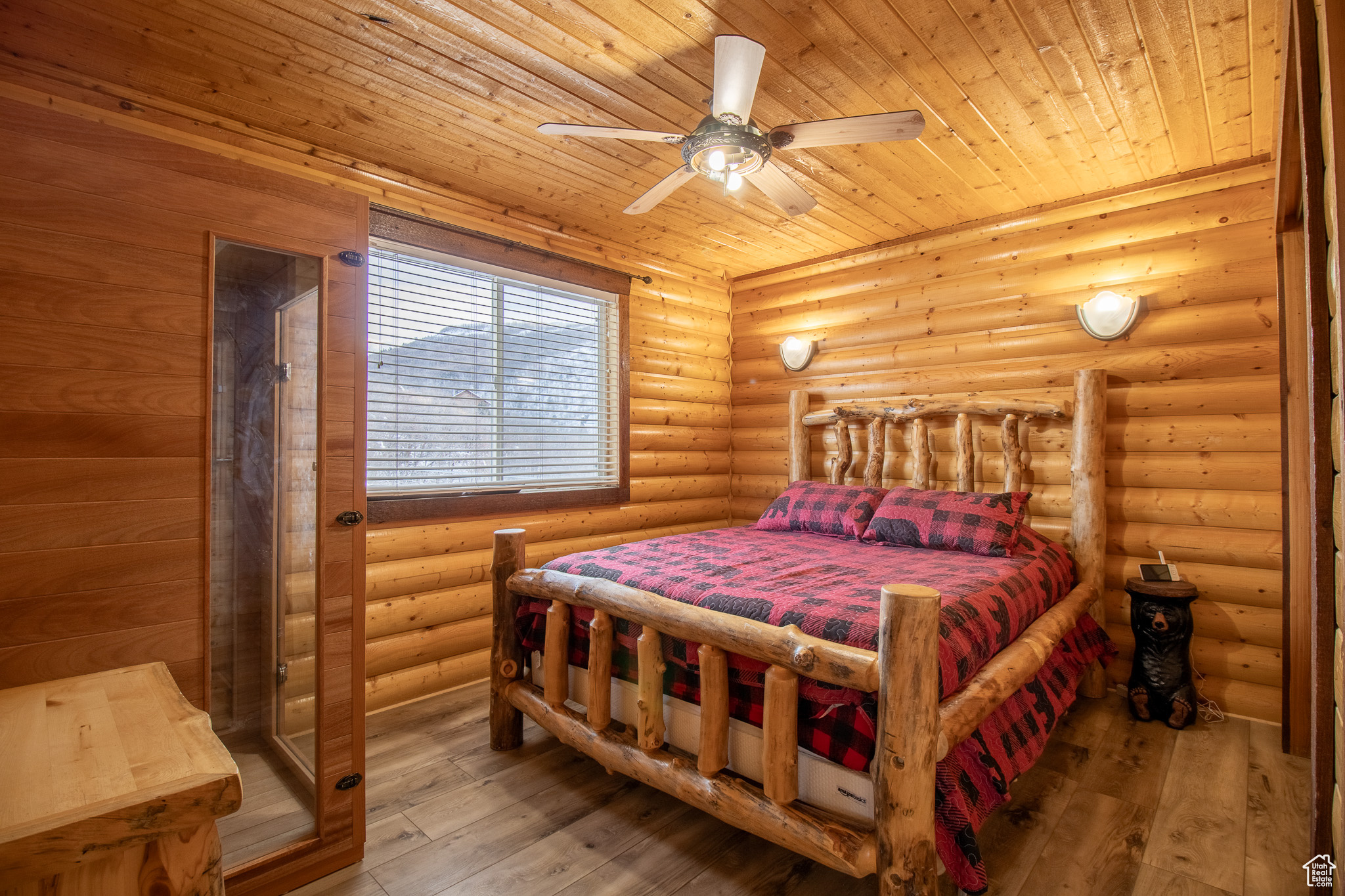 Bedroom featuring log walls, wood-type flooring, ceiling fan, and wood ceiling