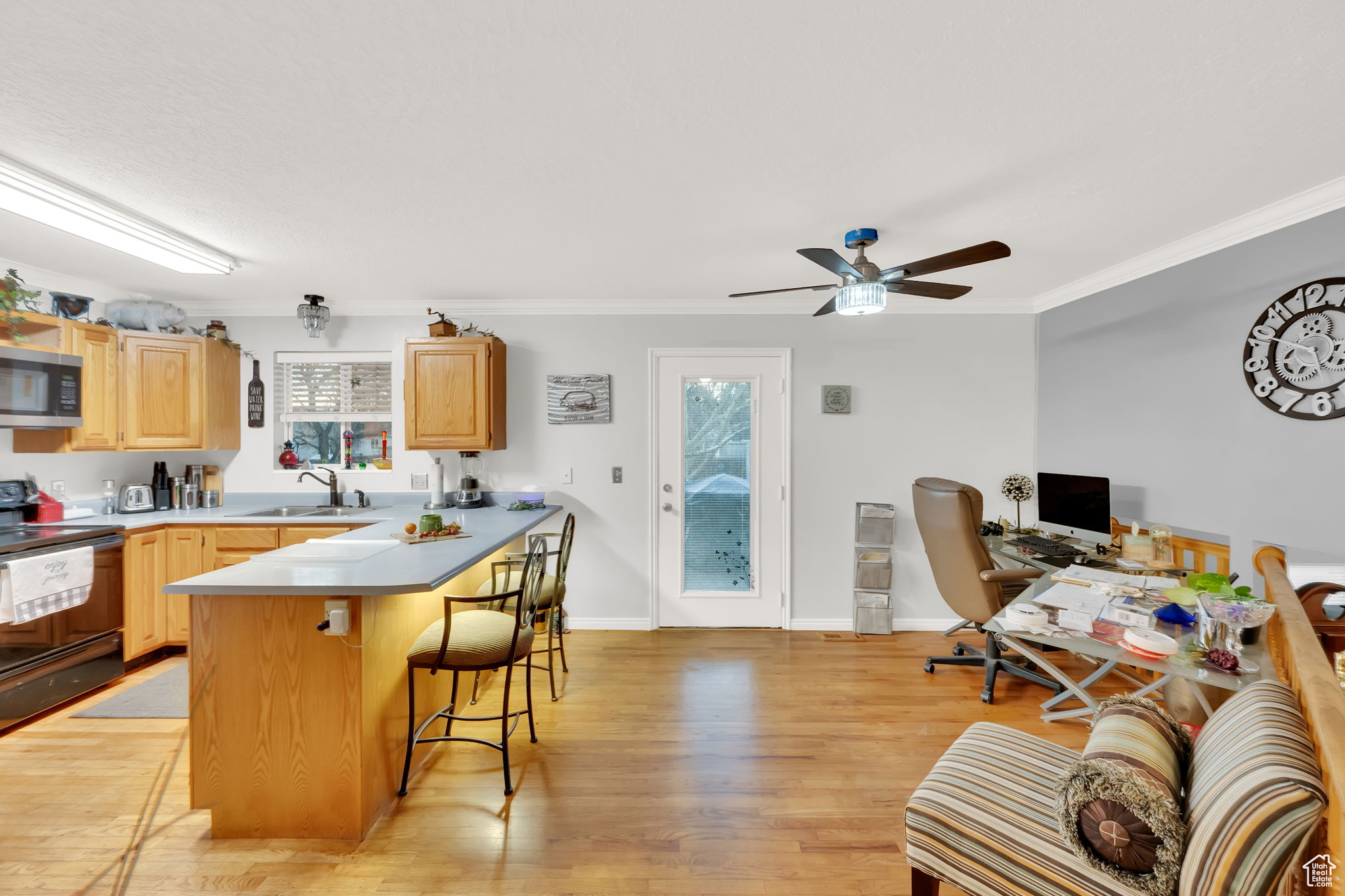 Kitchen with light brown cabinets, a kitchen breakfast bar, sink, electric range, and a wealth of natural light