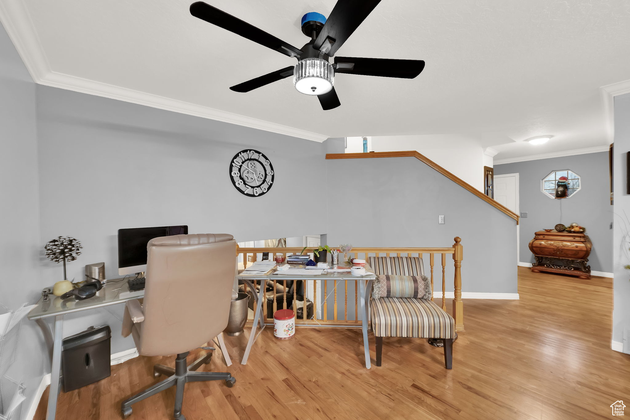 Home office with light hardwood / wood-style flooring, ceiling fan, and ornamental molding