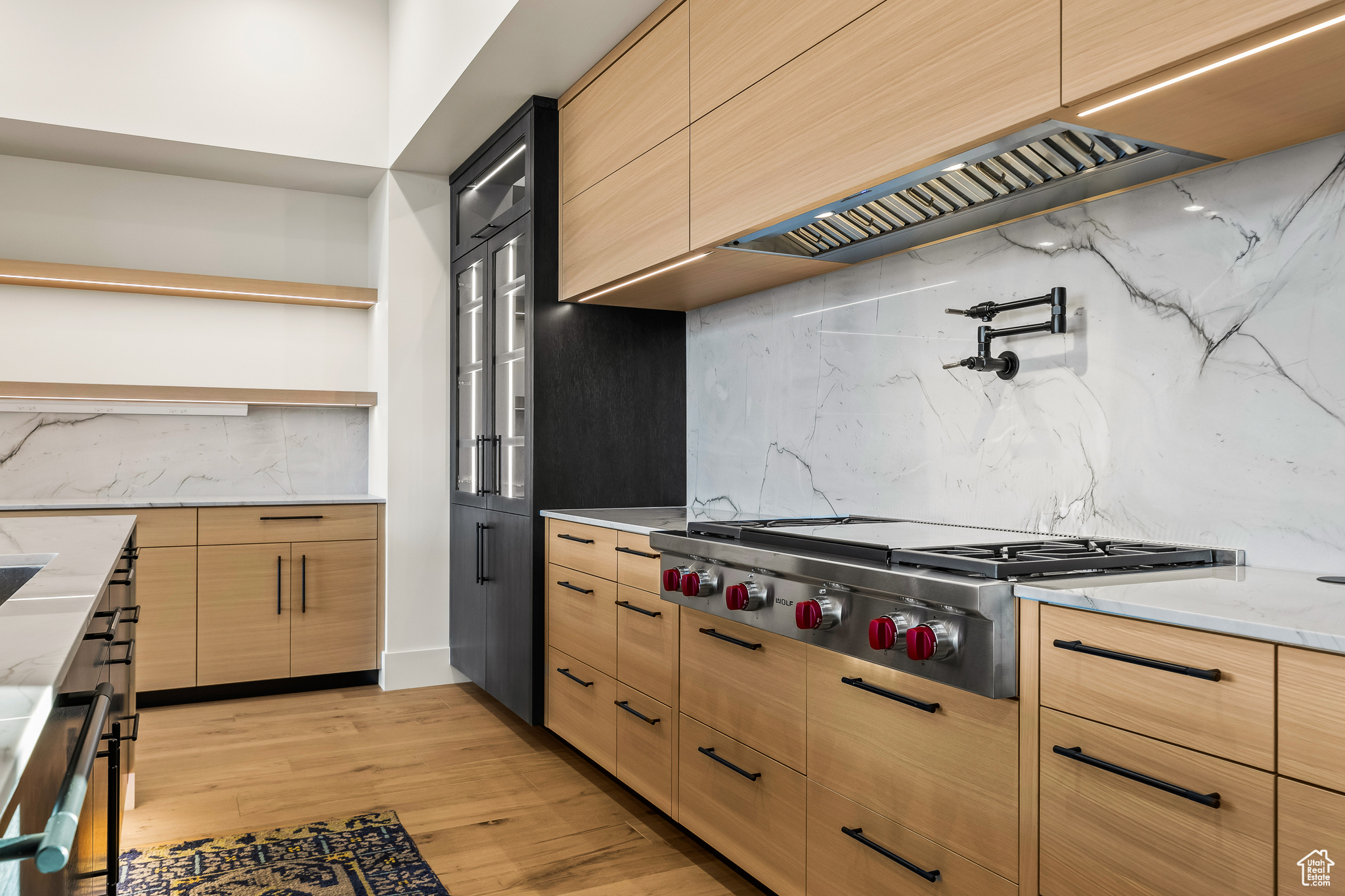 Kitchen featuring light stone countertops, stainless steel gas cooktop, tasteful backsplash, light hardwood / wood-style floors, and custom range hood