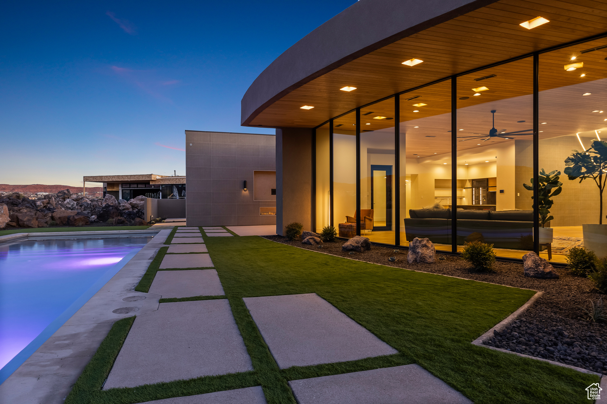 Pool at dusk with a yard, ceiling fan, and a patio area