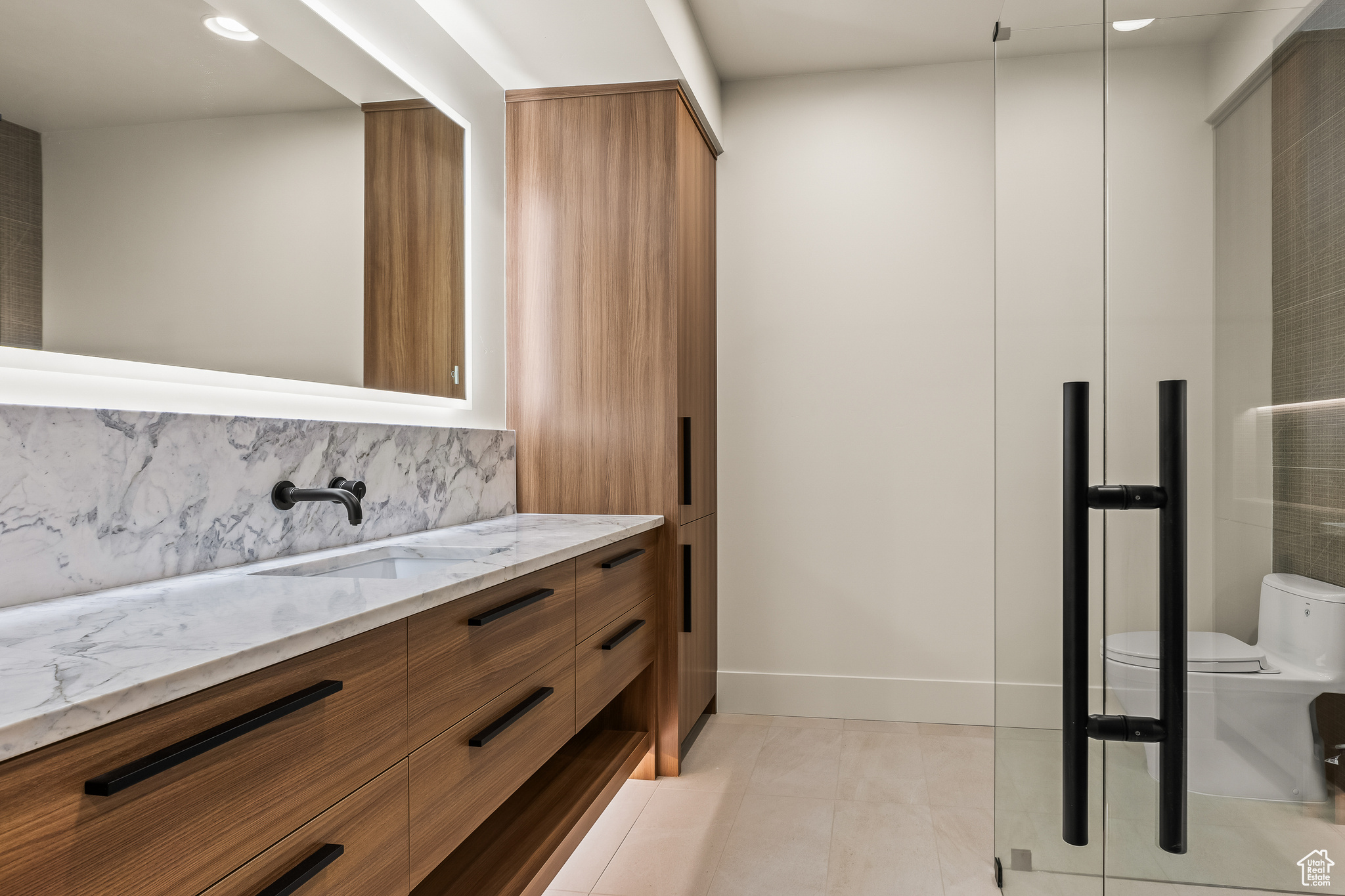 Bathroom featuring backsplash, tile patterned floors, vanity, and toilet