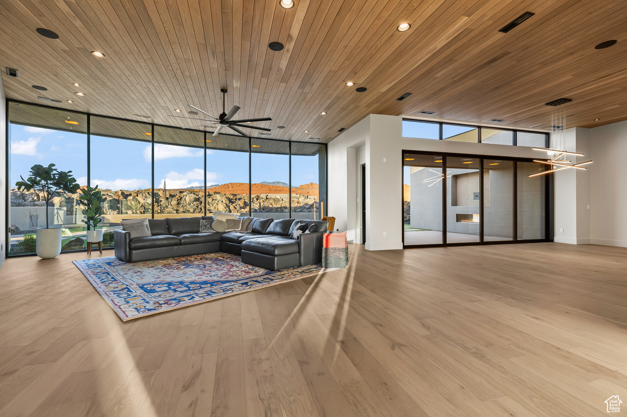 Living room with a wall of windows, a mountain view, light hardwood / wood-style floors, wood ceiling, and ceiling fan with notable chandelier