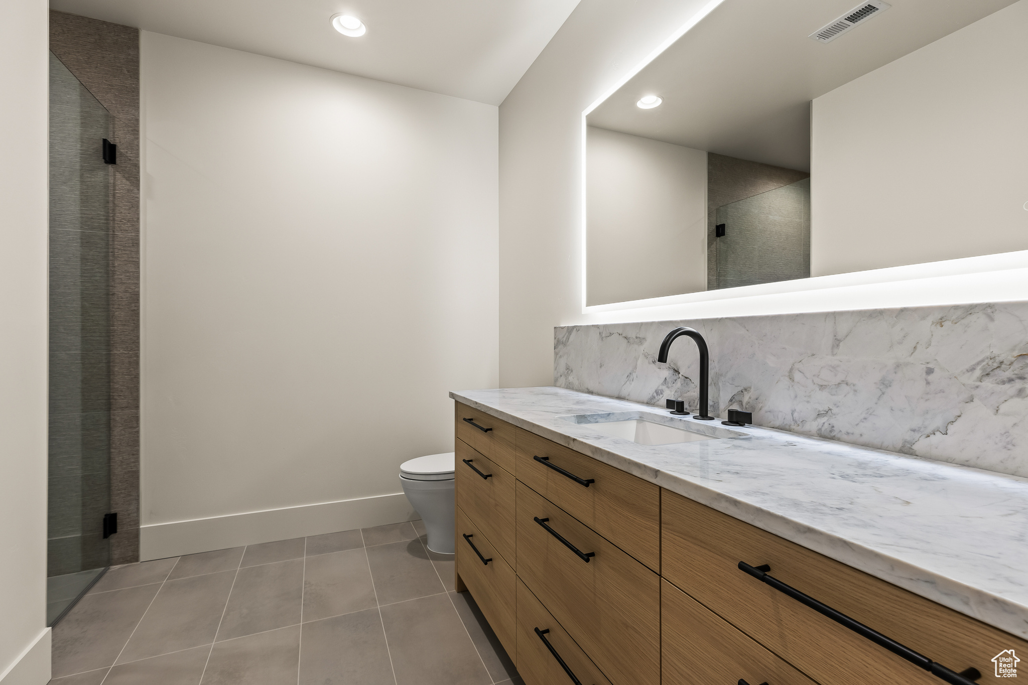 Bathroom featuring tile patterned flooring, vanity, an enclosed shower, and toilet