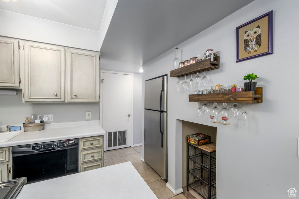 Kitchen featuring light tile patterned floors, black dishwasher, and stainless steel refrigerator