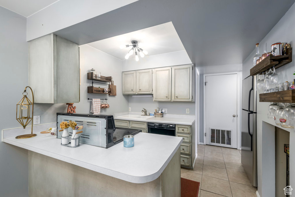 Kitchen with sink, kitchen peninsula, black dishwasher, and light tile patterned floors