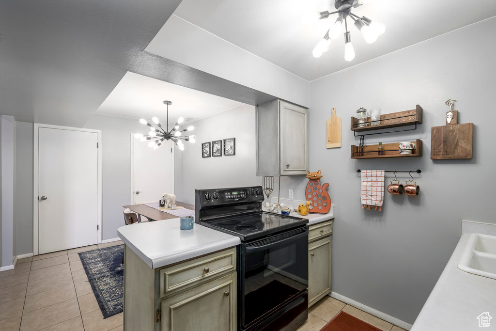 Kitchen with green cabinets, electric range, light tile patterned floors, and a notable chandelier