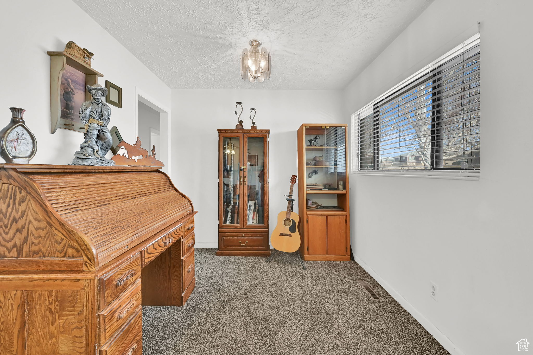 Miscellaneous room featuring dark colored carpet and a textured ceiling