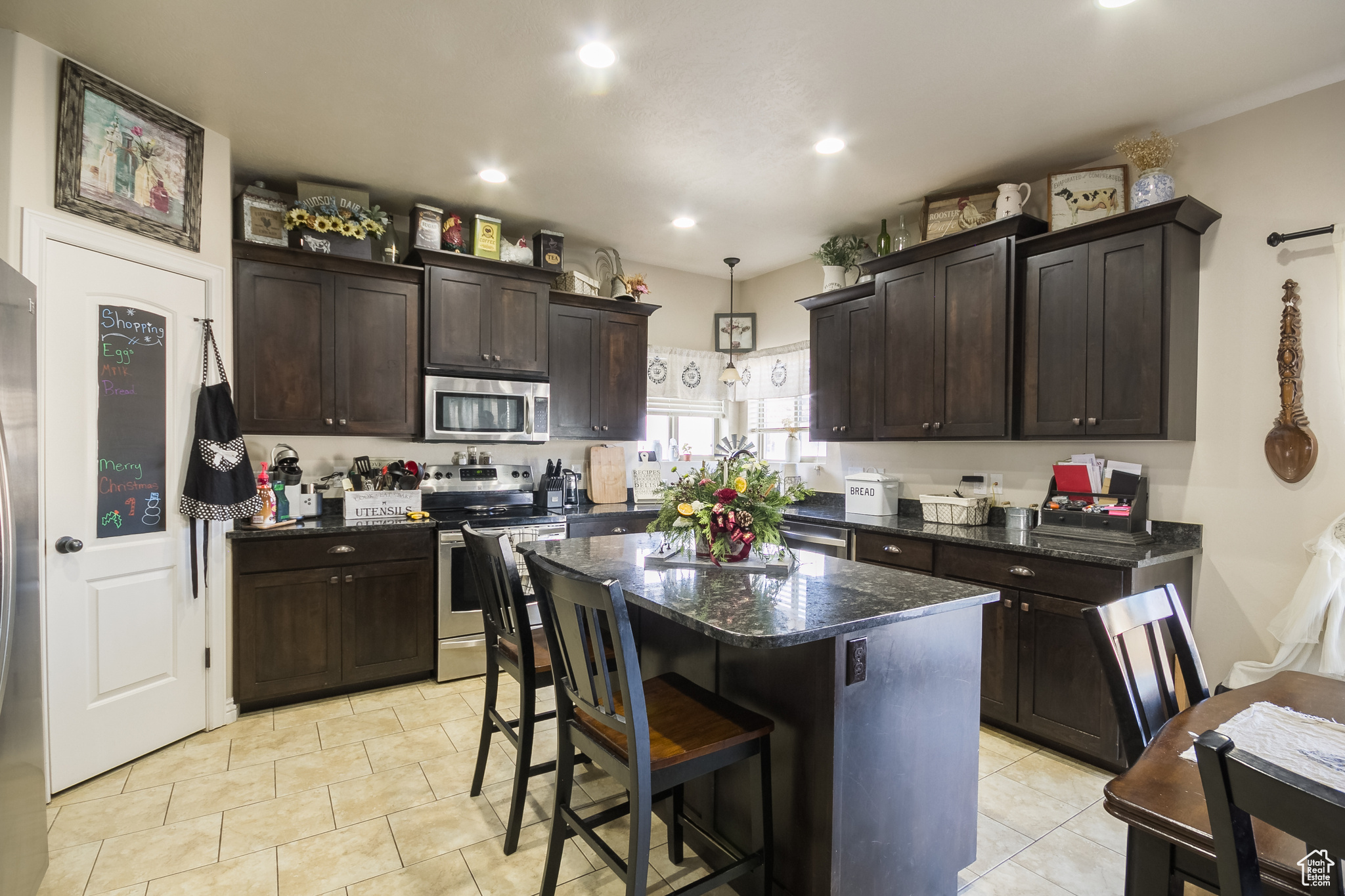 Kitchen featuring decorative light fixtures, a kitchen island, dark brown cabinetry, and stainless steel appliances