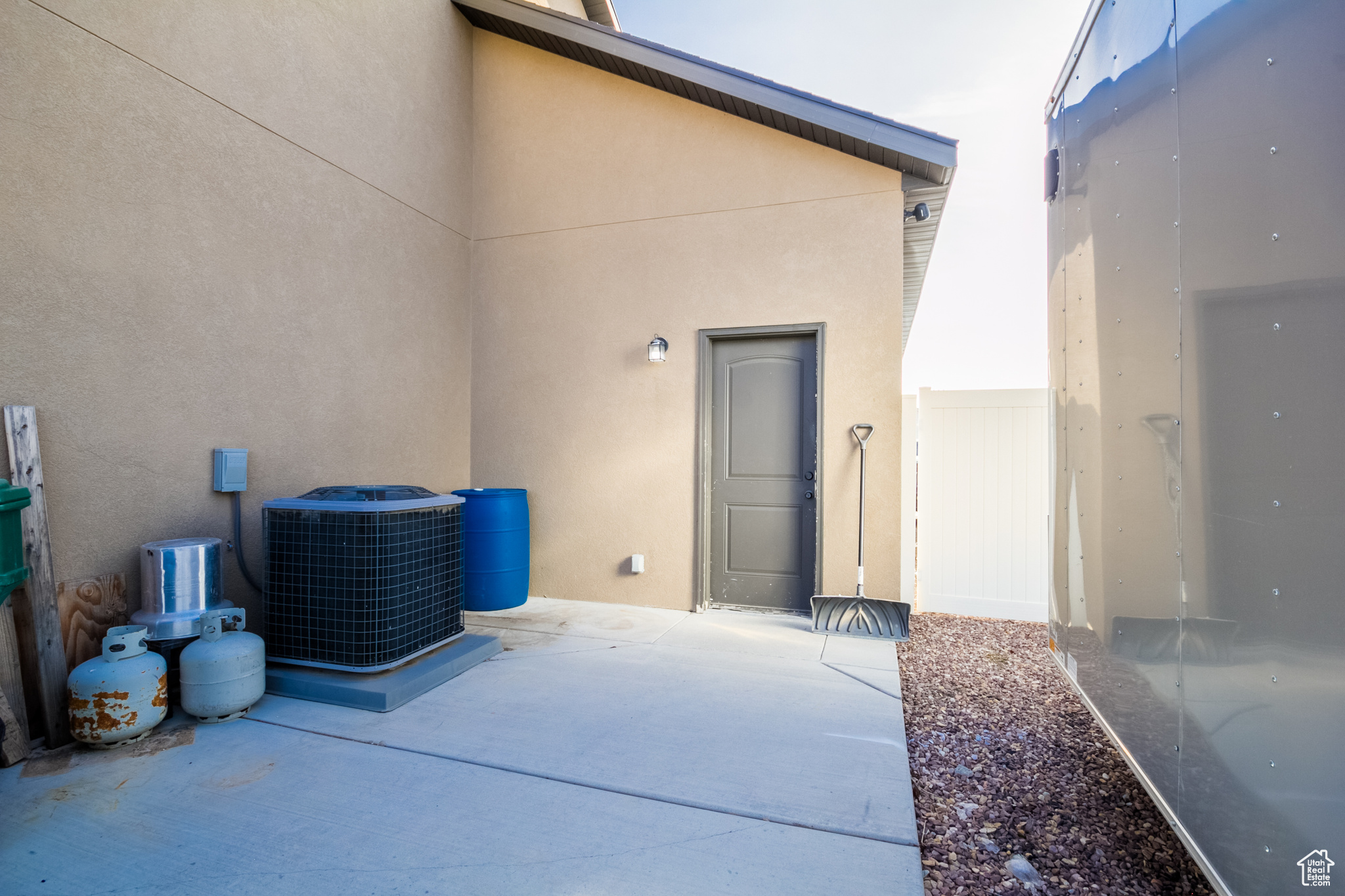 View of exterior door from garage with cooling unit and extra parking