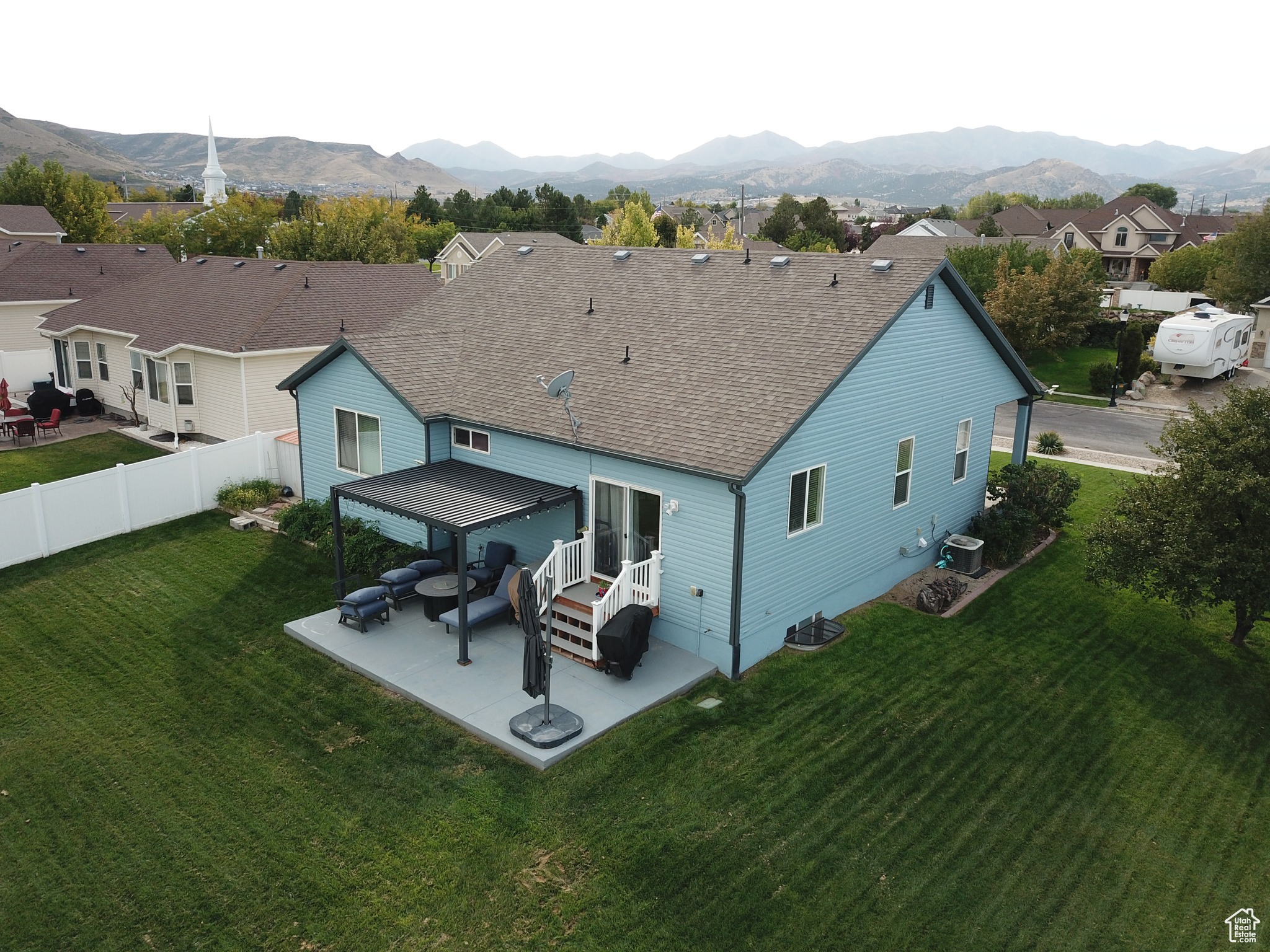 Rear view of property featuring central air condition unit, a patio area, a mountain view, and a yard