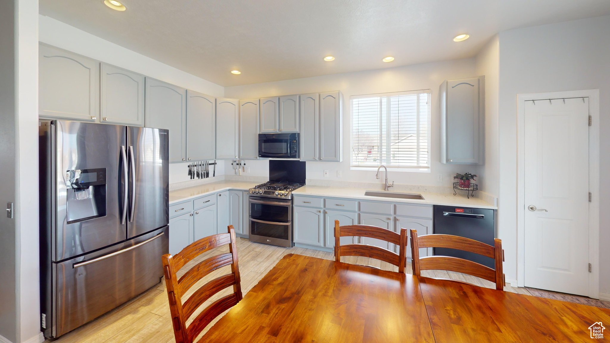 Kitchen with sink, light hardwood / wood-style floors, and black appliances