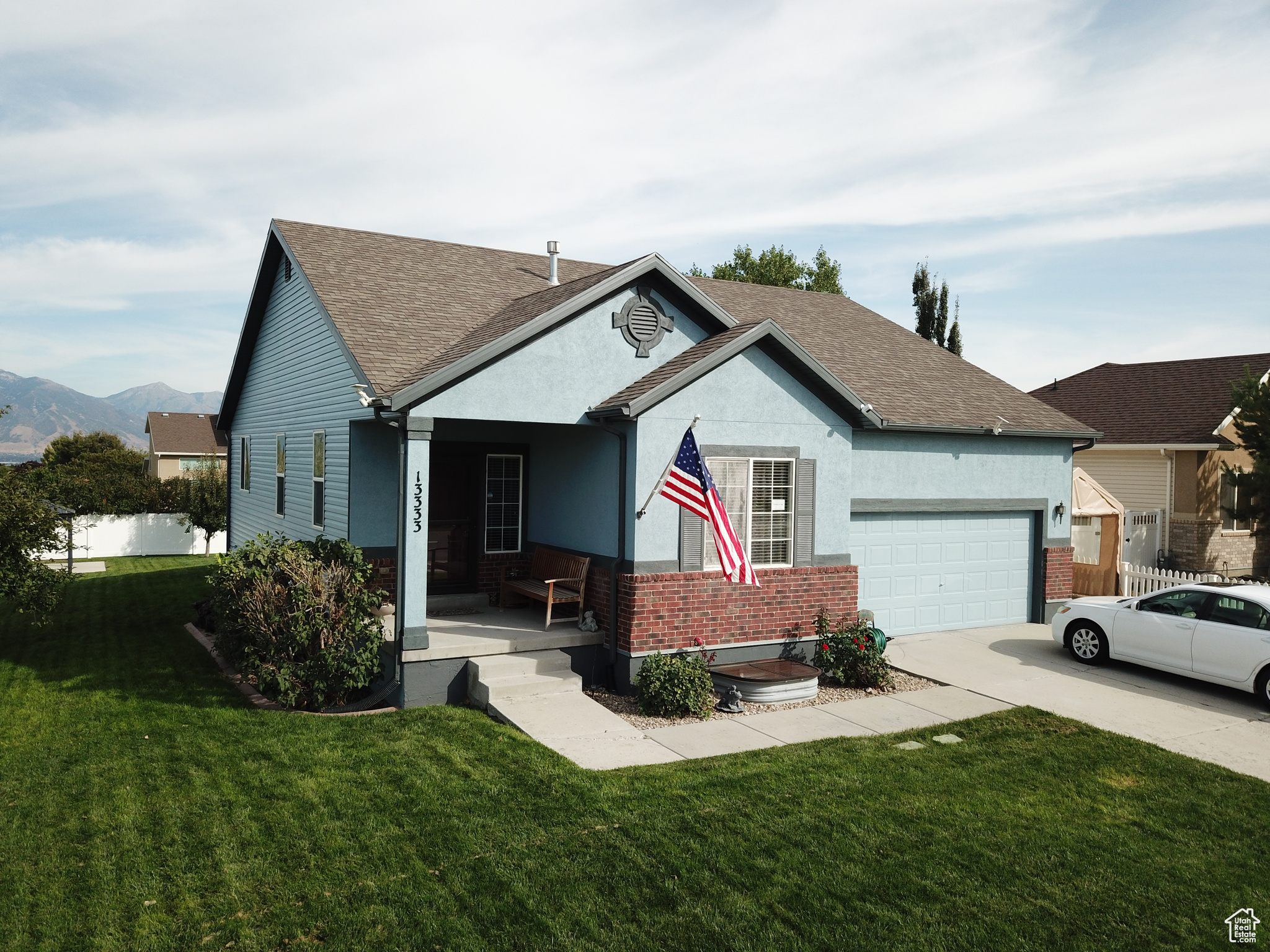 View of front of house with covered porch, a garage, and a front lawn