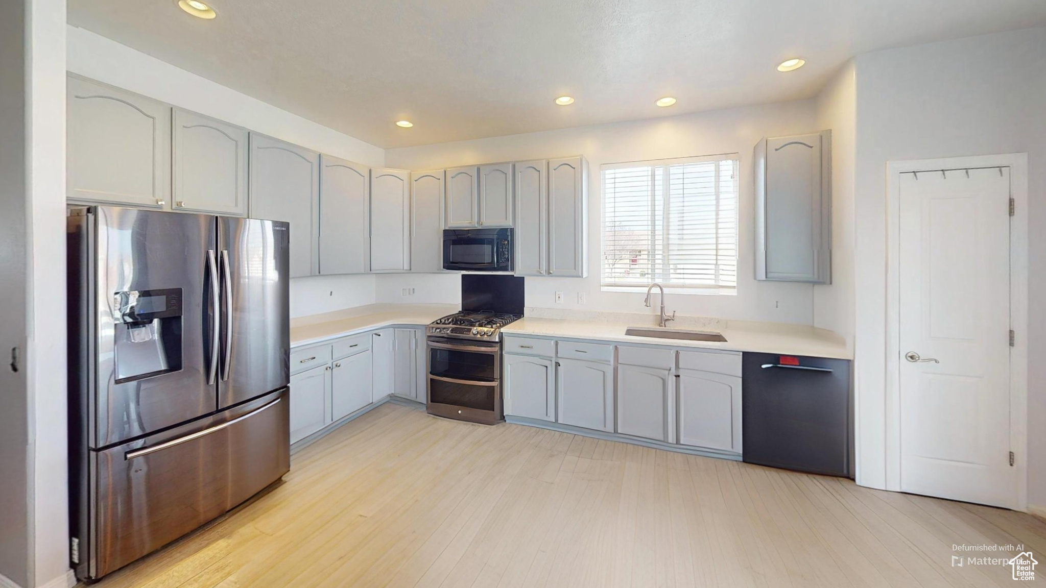 Virtually un-staged. Kitchen with sink, gray cabinets, light hardwood / wood-style floors, and black appliances