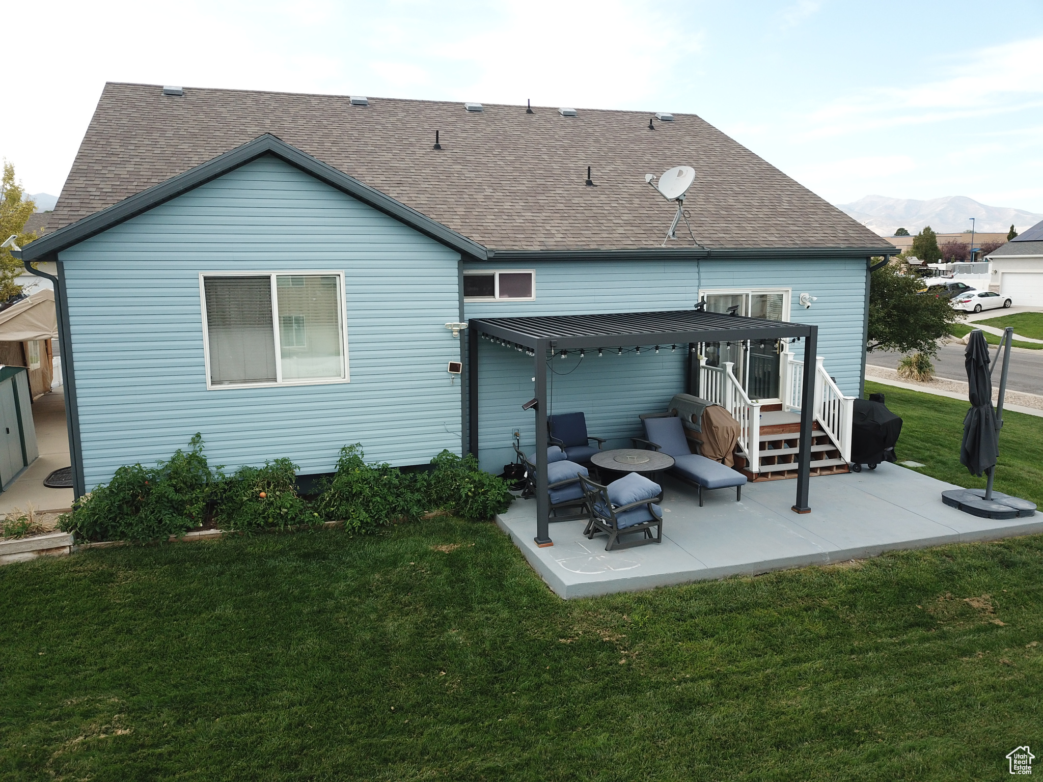 Rear view of property with a mountain view, a patio, and a lawn