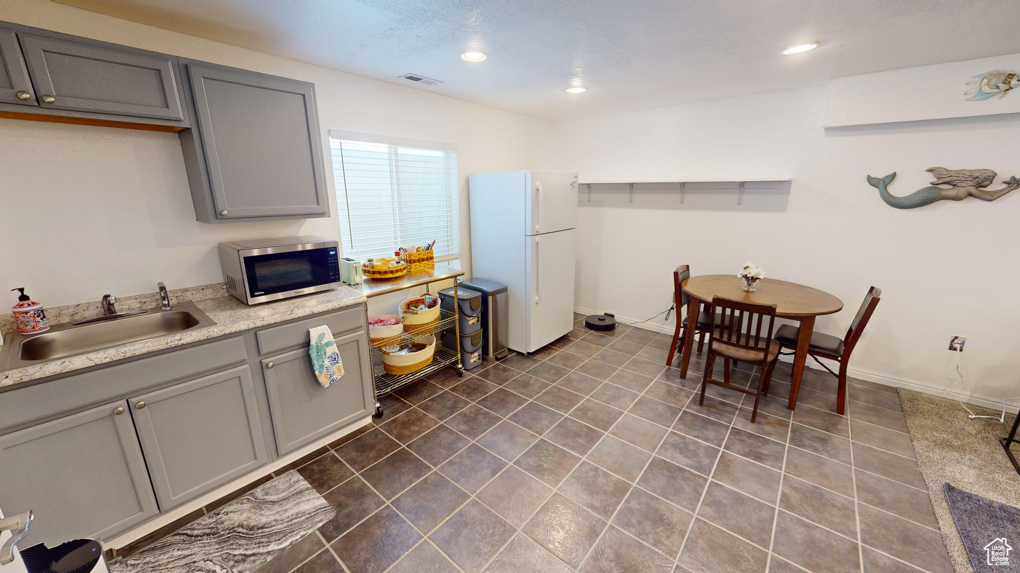 Kitchen featuring gray cabinets, sink, and white refrigerator