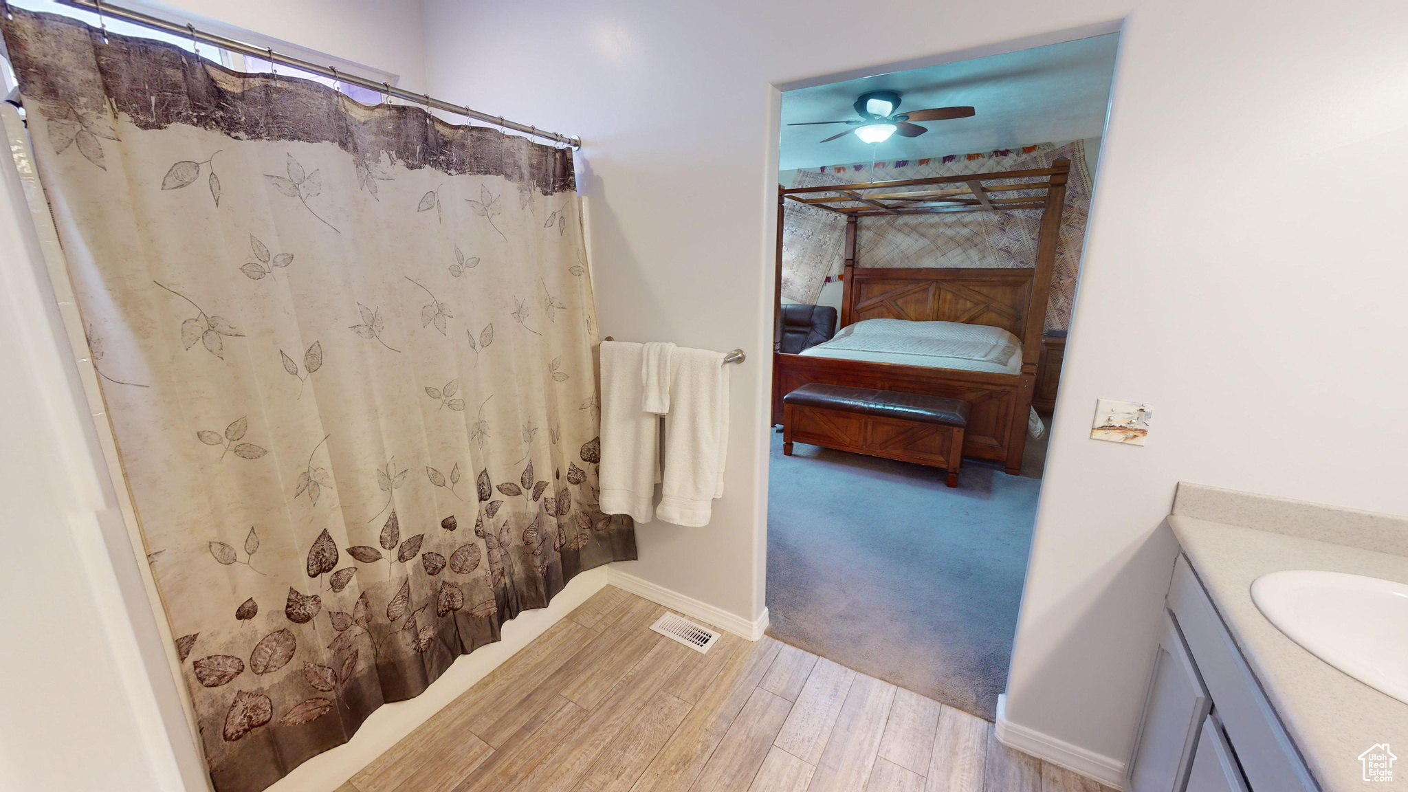 Bathroom featuring hardwood / wood-style floors, vanity, ceiling fan, and curtained shower