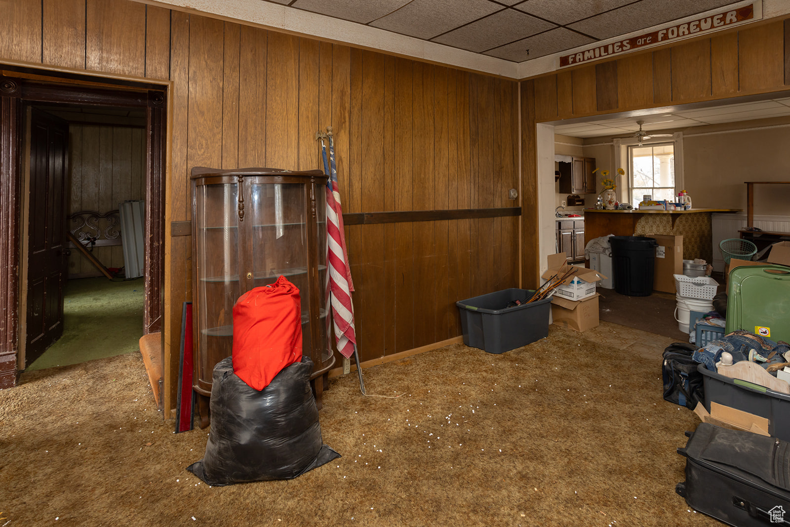 Miscellaneous room with a drop ceiling, wood walls, and ceiling fan