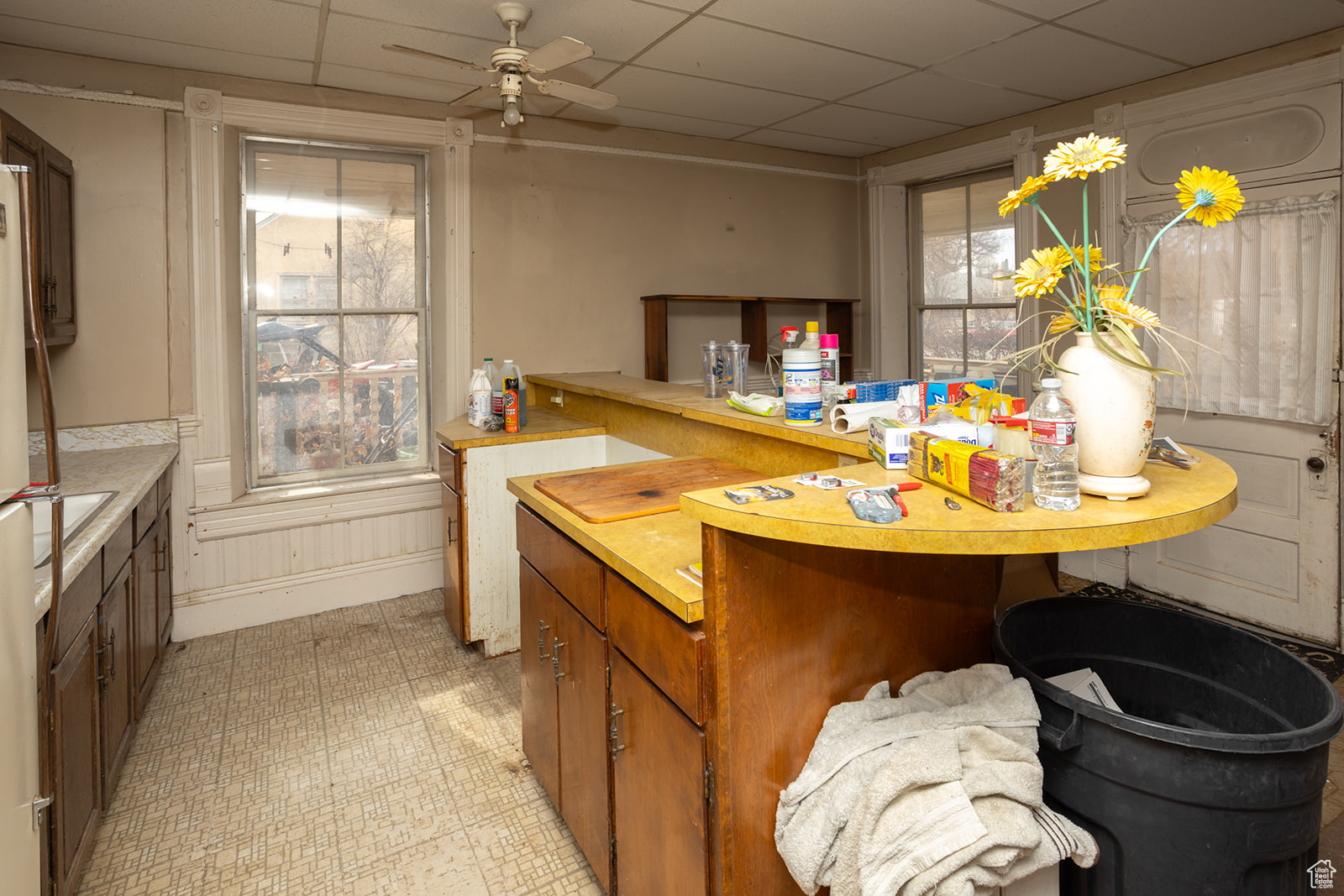 Kitchen featuring ceiling fan, a drop ceiling, and a healthy amount of sunlight