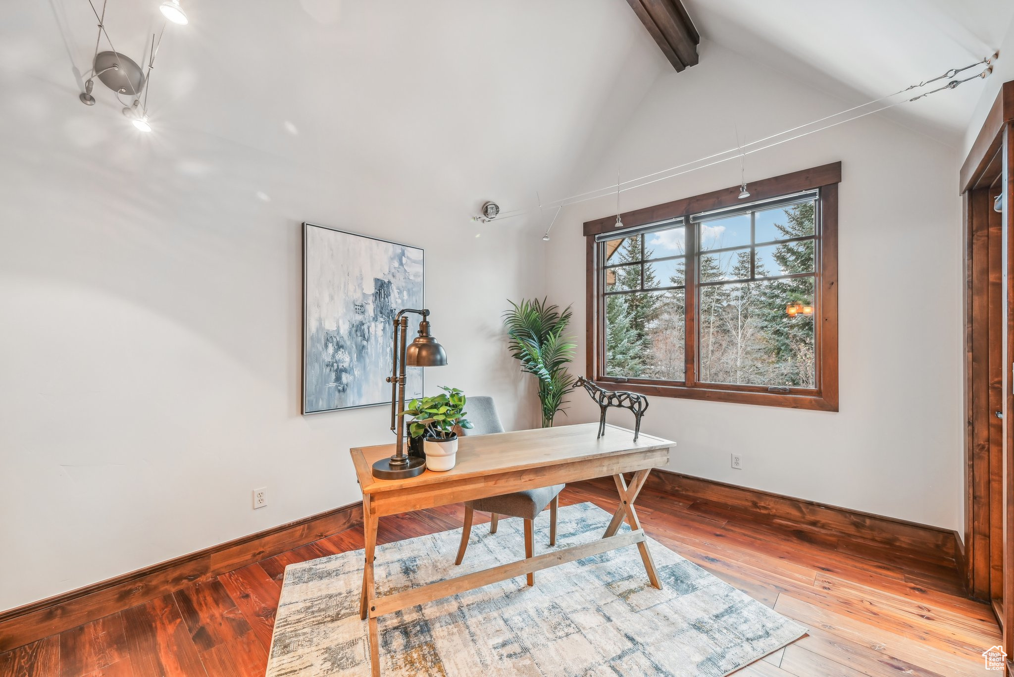 Office space with wood-type flooring and vaulted ceiling with beams