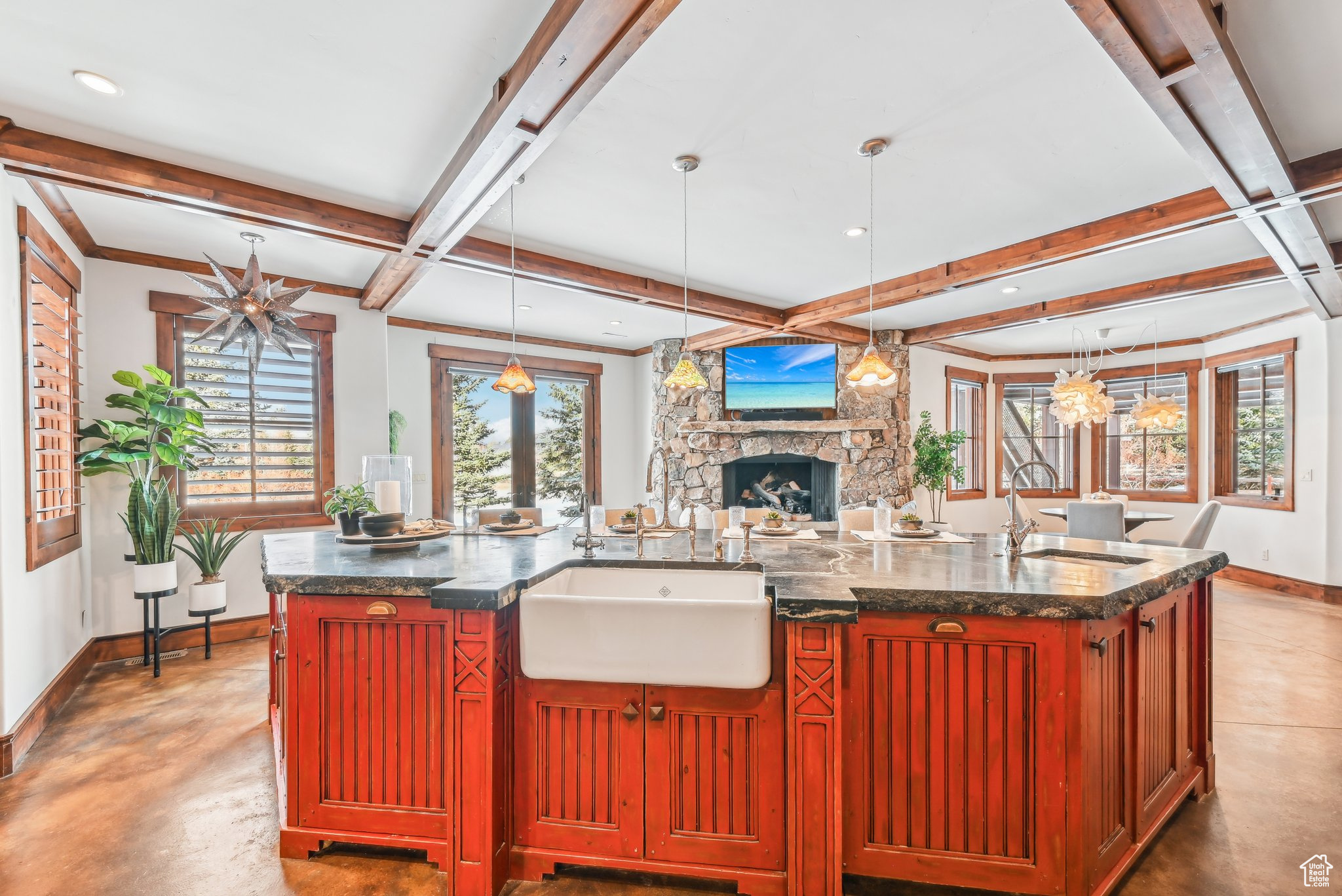 Kitchen featuring a large island with sink, hanging light fixtures, sink, a fireplace, and beamed ceiling