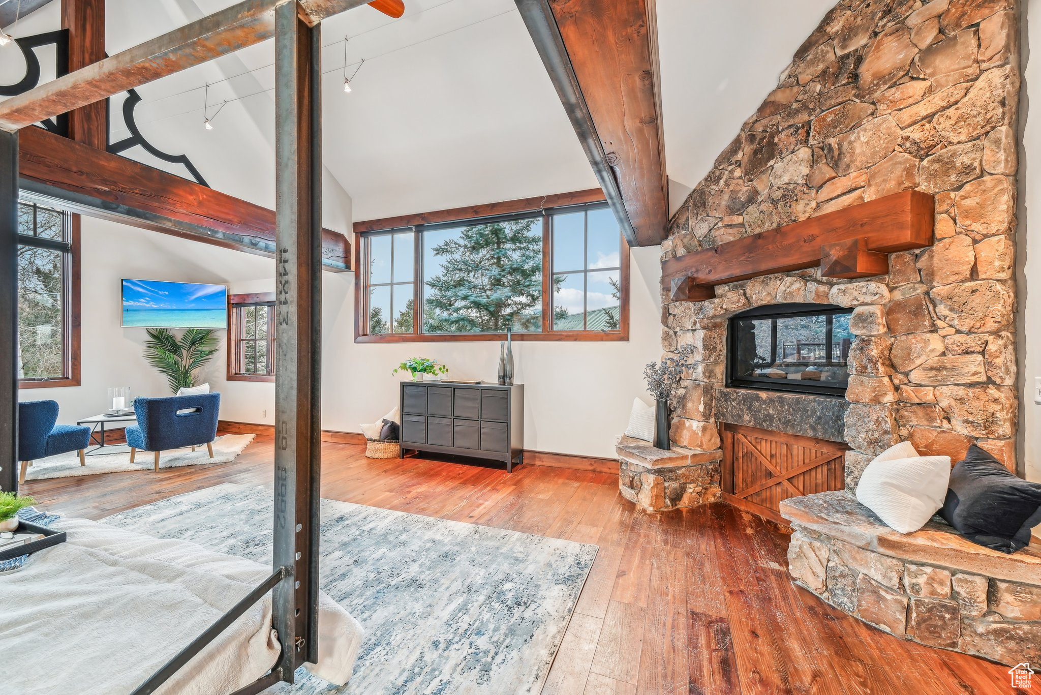 Living room with rail lighting, beamed ceiling, high vaulted ceiling, hardwood / wood-style floors, and a fireplace