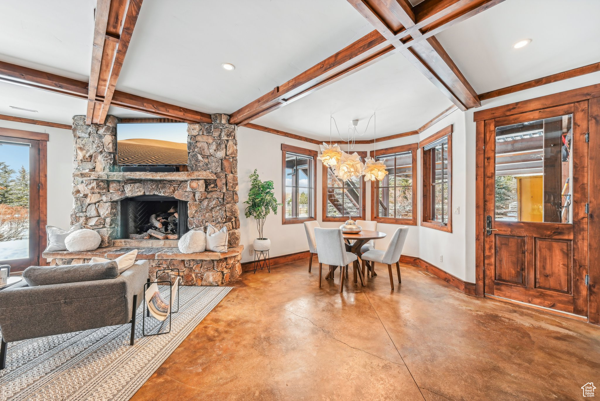 Living room featuring coffered ceiling, a healthy amount of sunlight, a stone fireplace, and concrete floors