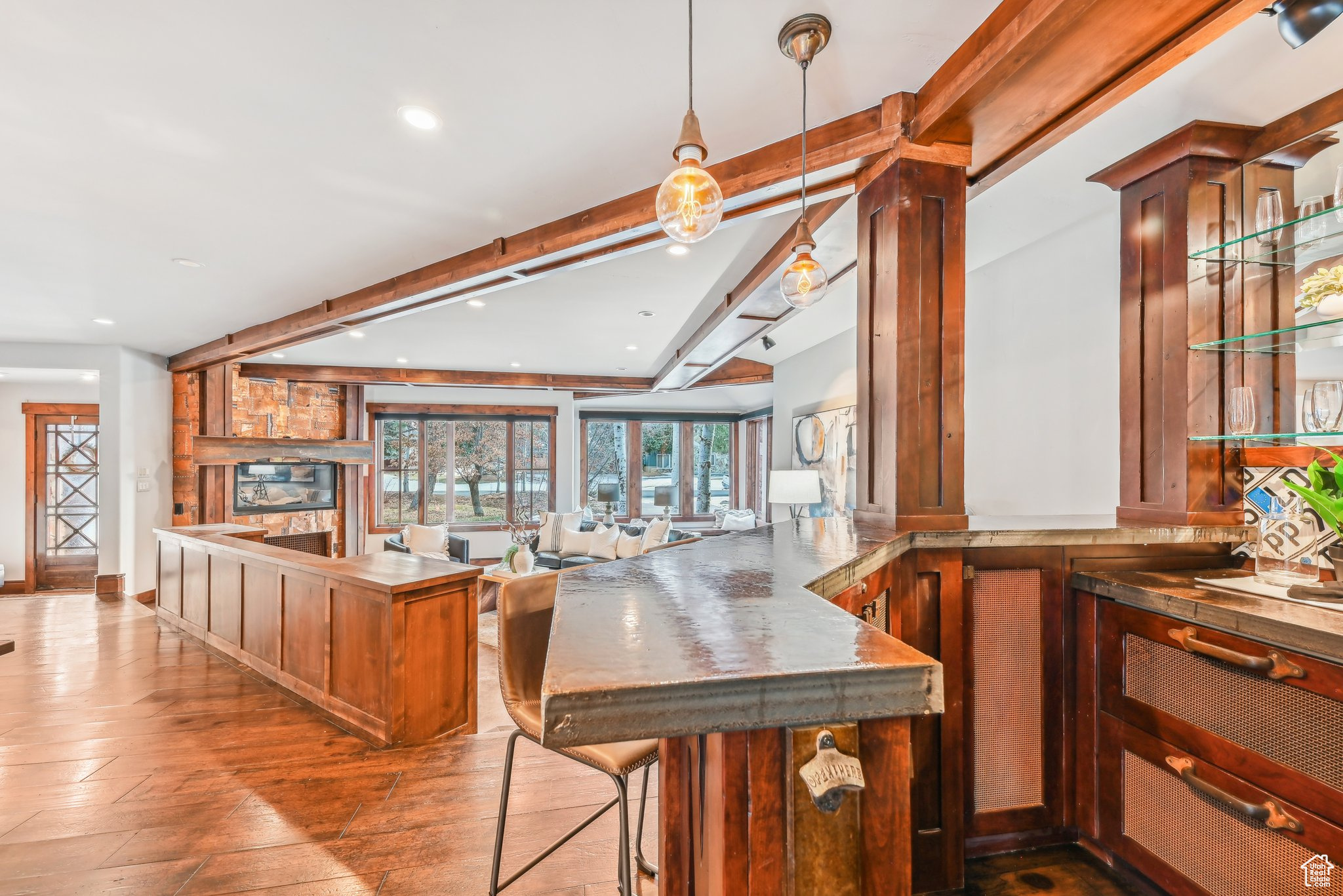 Kitchen with a kitchen breakfast bar, kitchen peninsula, hanging light fixtures, beamed ceiling, and wood-type flooring