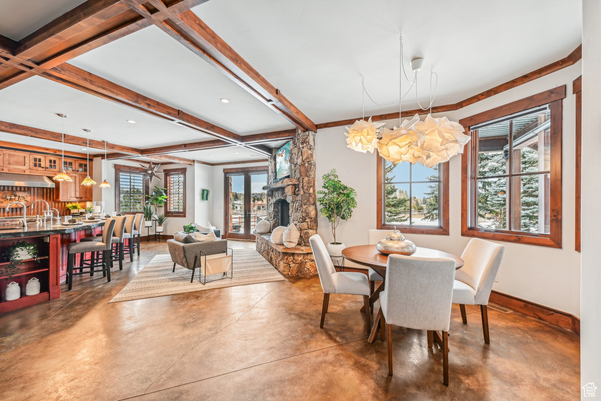 Dining space featuring beamed ceiling, concrete flooring, and an inviting chandelier