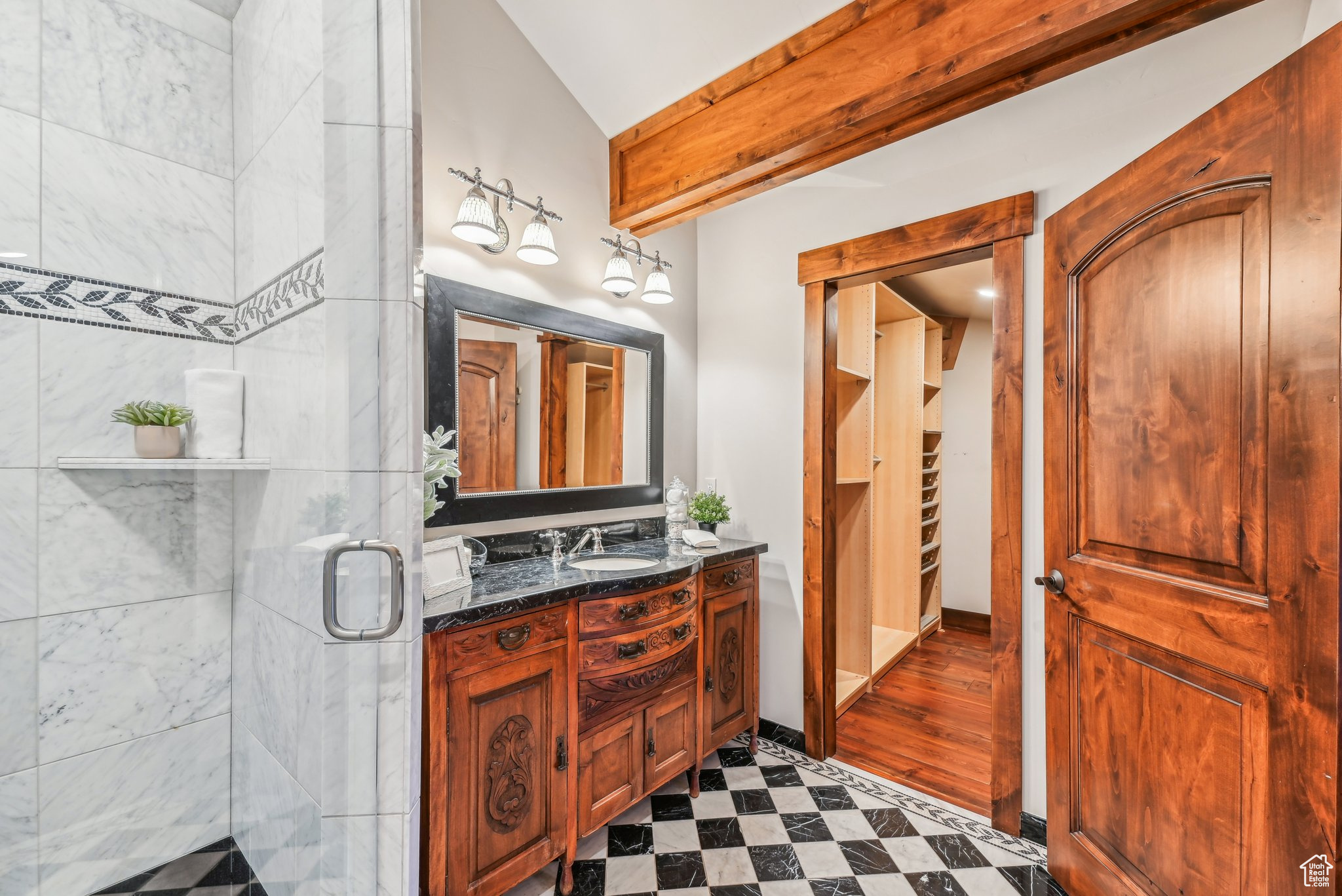 Bathroom featuring vanity, a shower with shower door, and vaulted ceiling