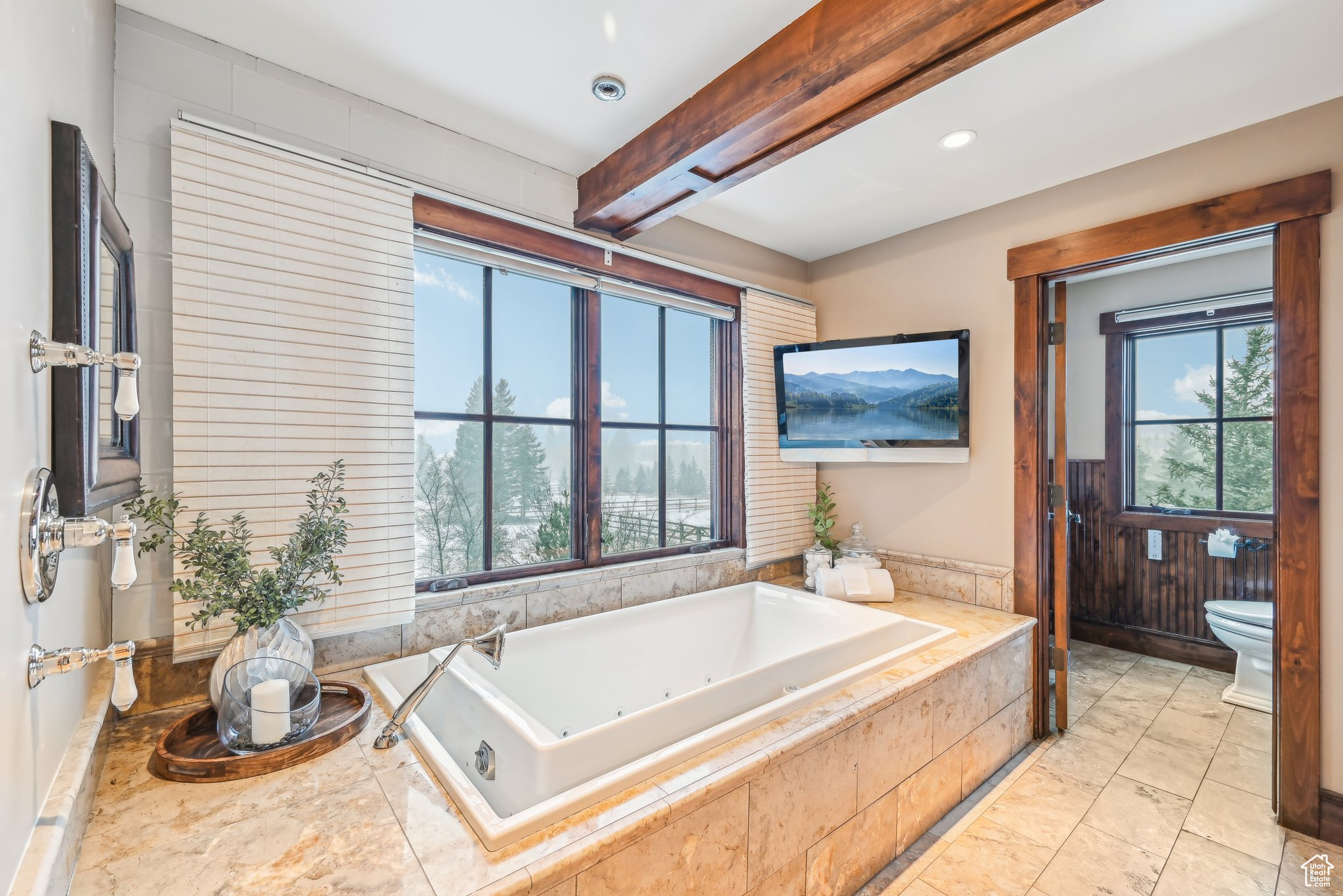 Bathroom featuring beam ceiling, a relaxing tiled tub, and toilet