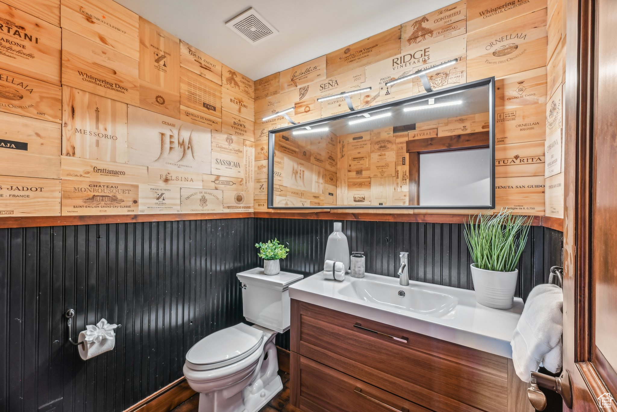 Bathroom with vanity, toilet, and wooden walls