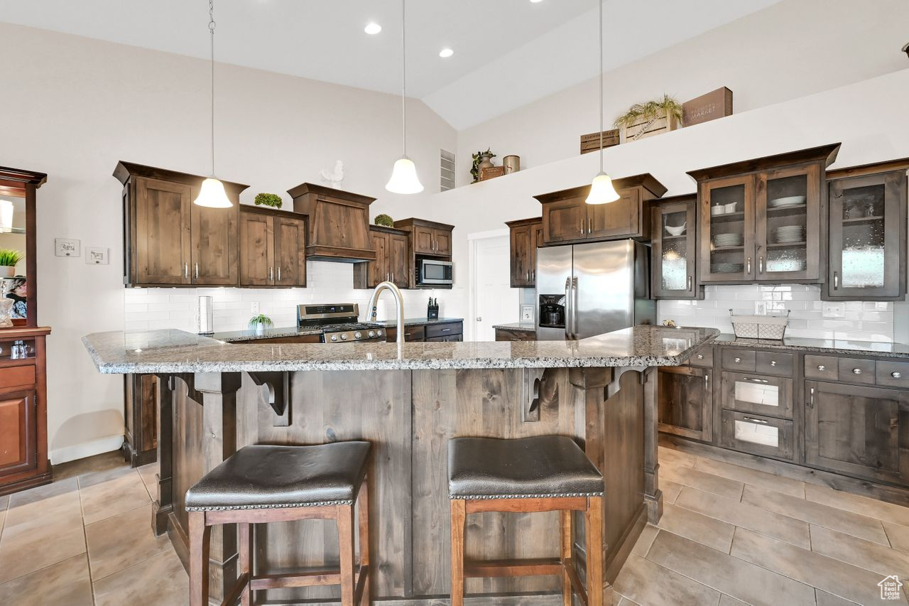 Kitchen with a kitchen bar, tasteful backsplash, granite counters, stainless steel appliances.