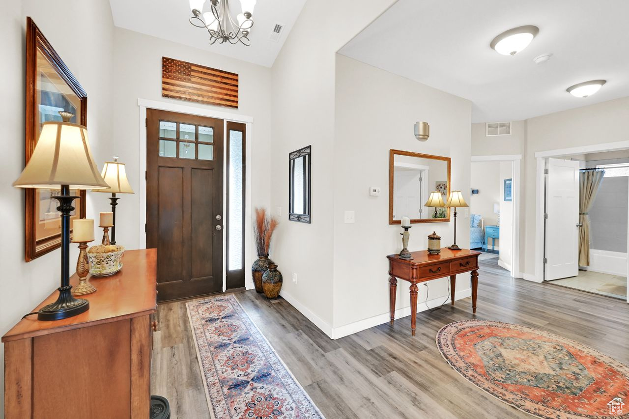 Entrance foyer with hardwood / wood-style flooring and an inviting chandelier