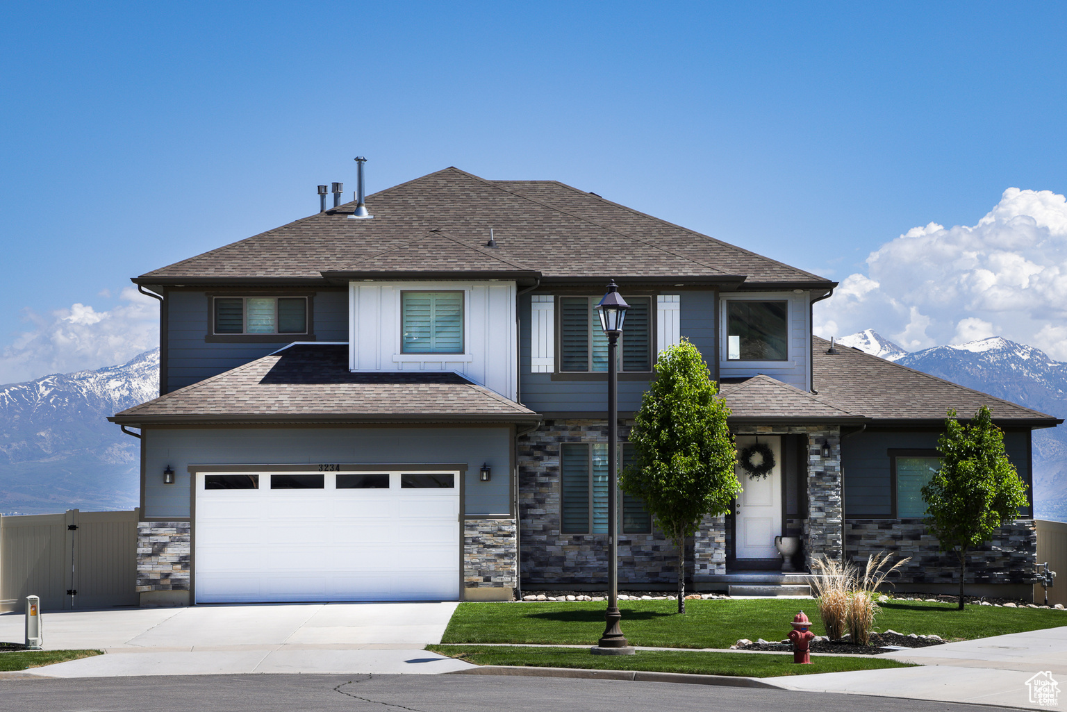 View of front of property featuring a mountain view, a front lawn, and a garage