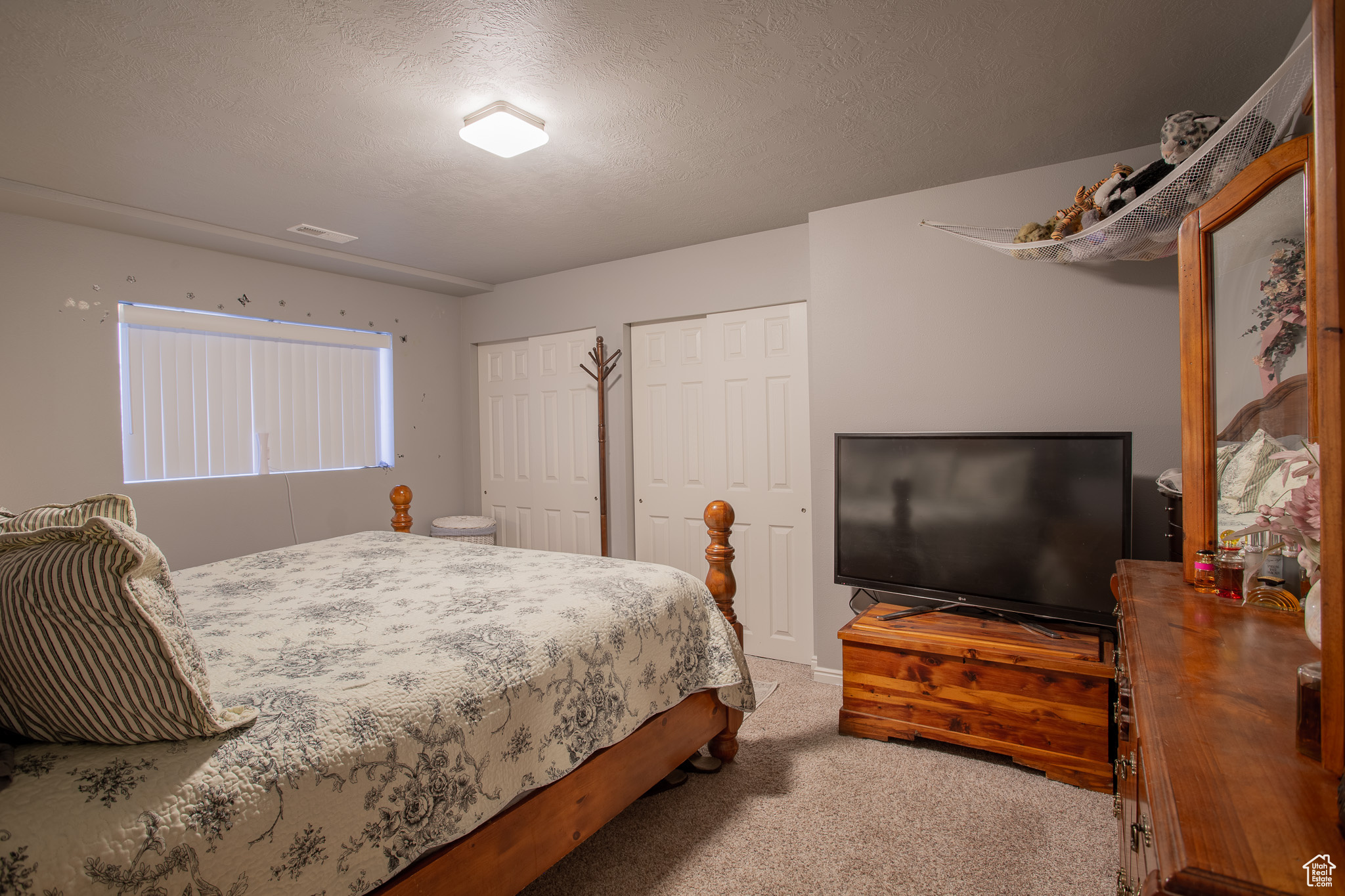 Bedroom featuring carpet flooring, a textured ceiling, and two closets