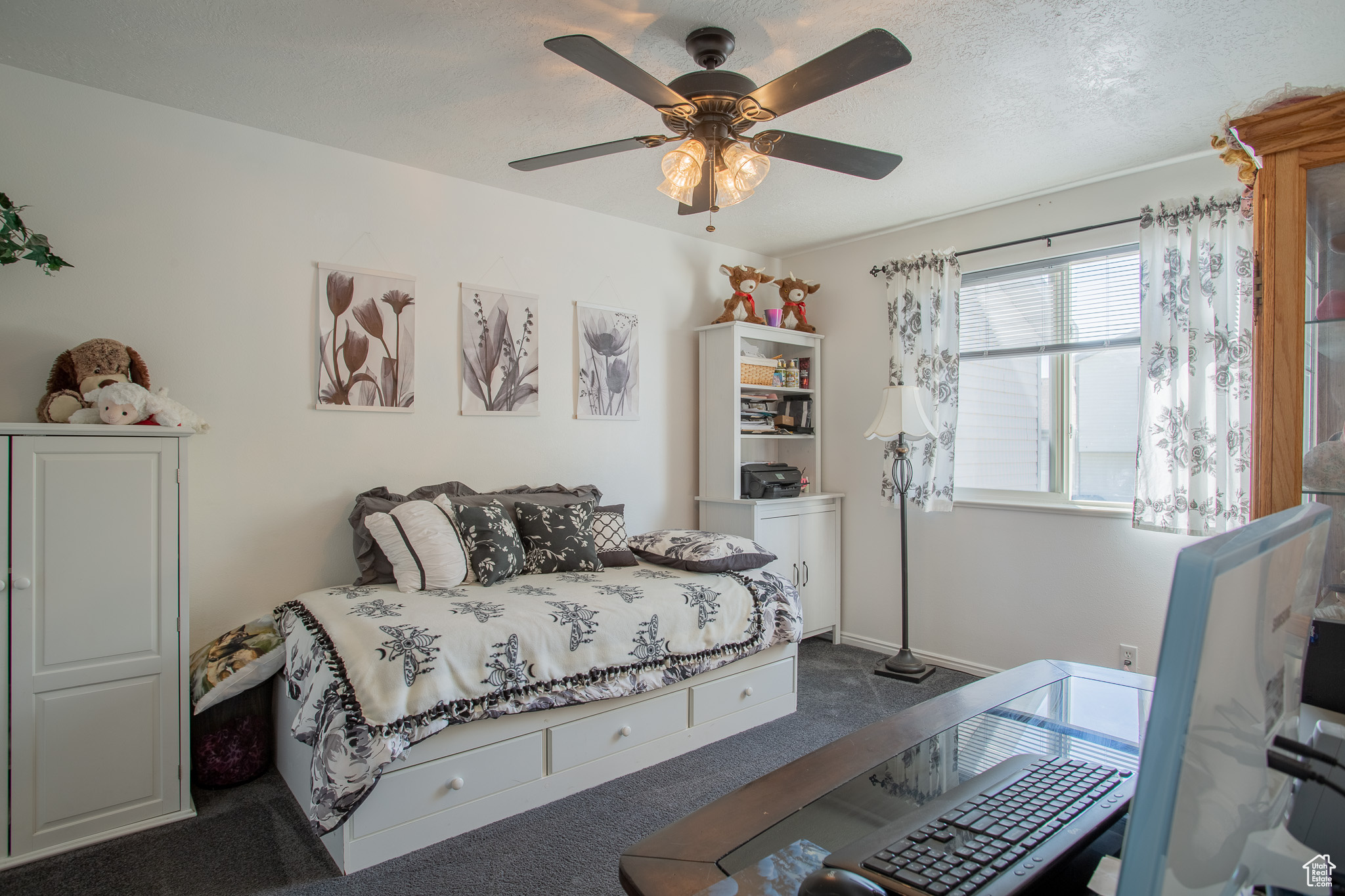 Carpeted bedroom featuring ceiling fan and a textured ceiling