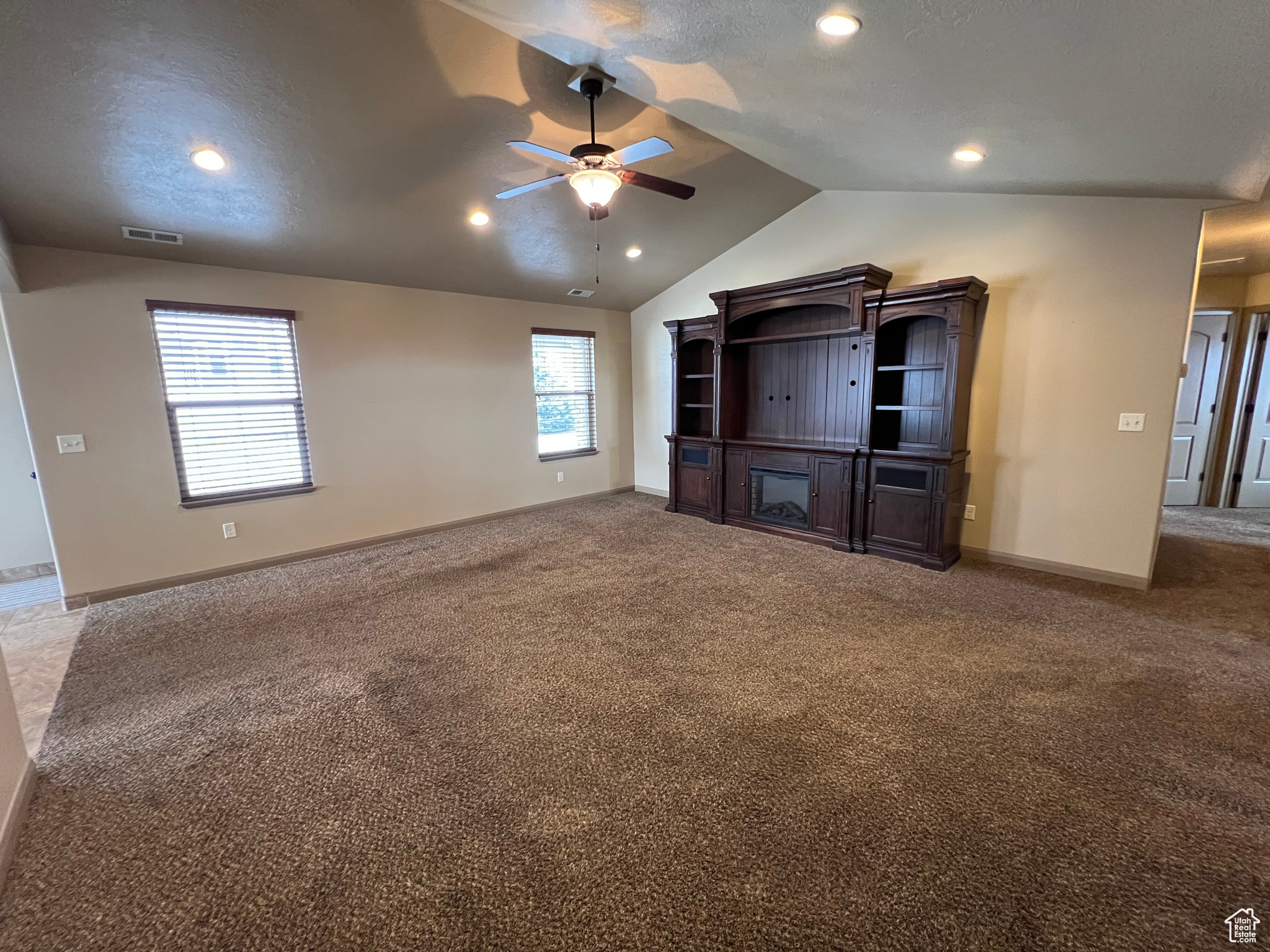 Unfurnished living room with carpet, ceiling fan, and lofted ceiling