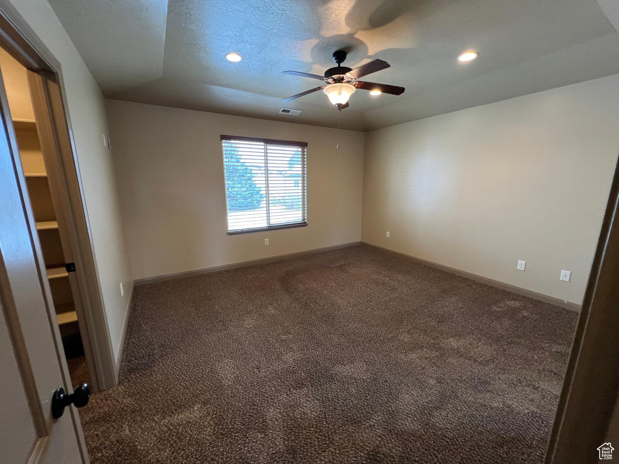 Carpeted spare room featuring a textured ceiling, ceiling fan, and lofted ceiling