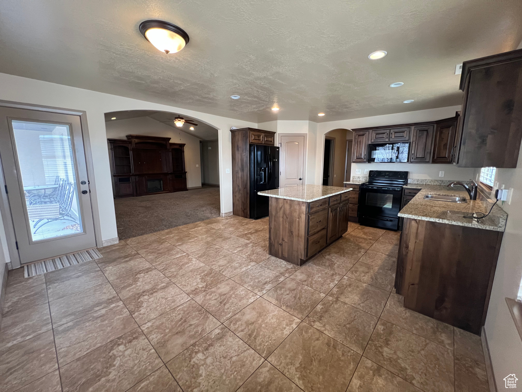 Kitchen featuring a center island, black appliances, sink, ceiling fan, and dark brown cabinets