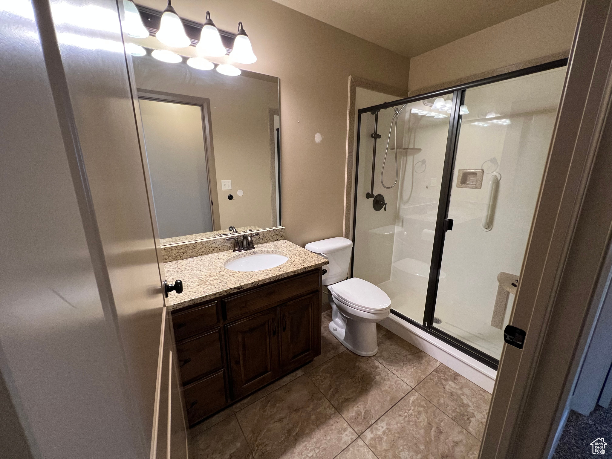 Bathroom featuring tile patterned floors, vanity, toilet, and a shower with shower door