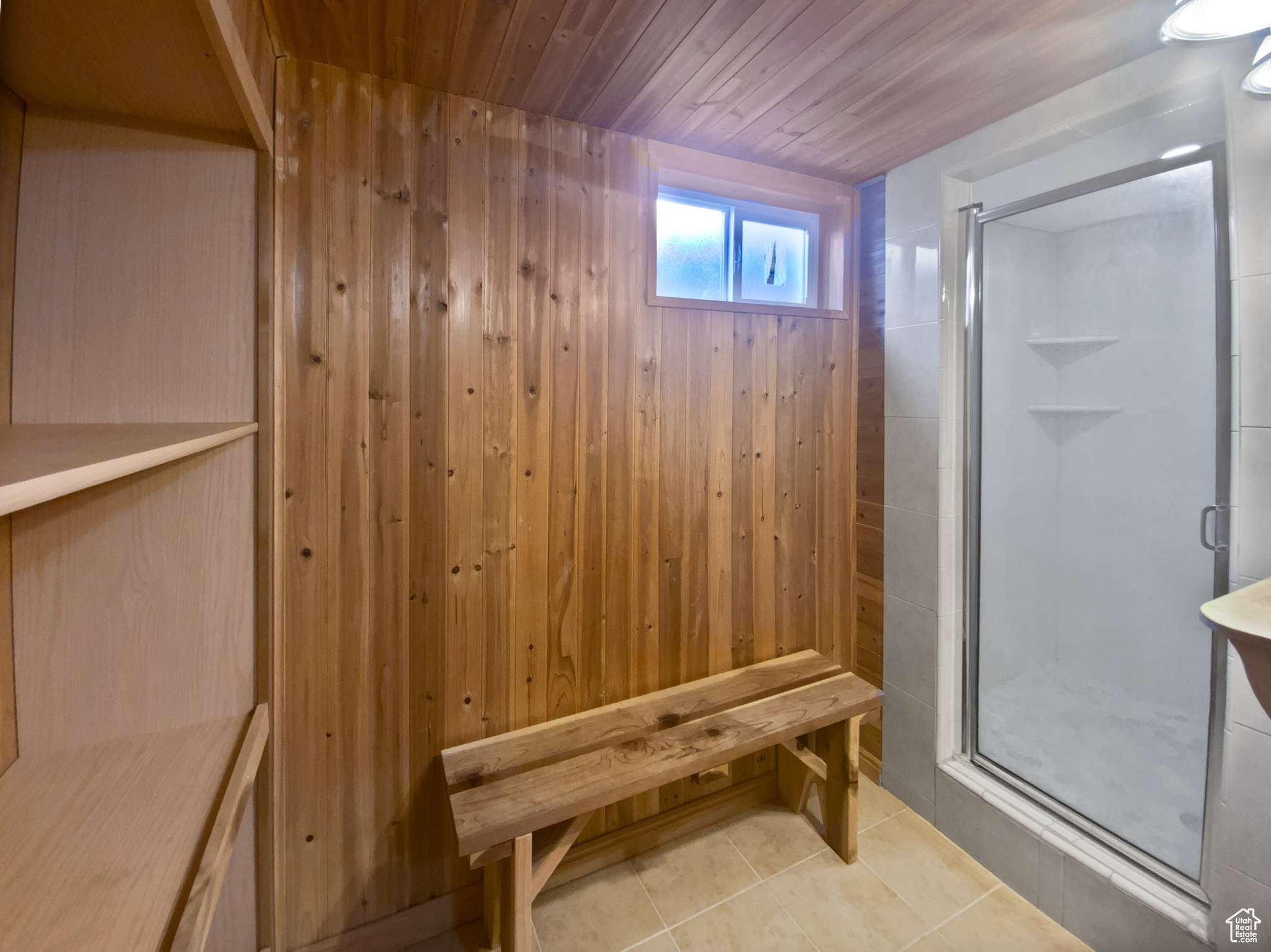 Bathroom with tile patterned flooring, wooden walls, and a shower with shower door