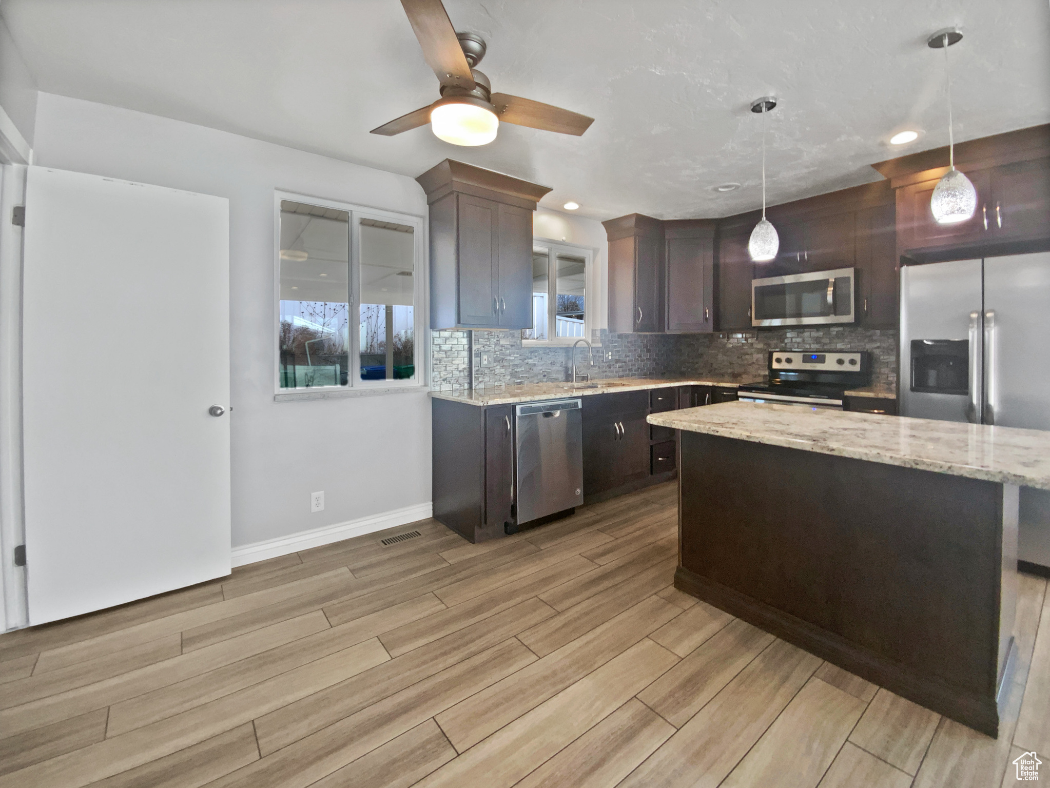 Kitchen featuring dark brown cabinetry, stainless steel appliances, sink, a center island, and hanging light fixtures