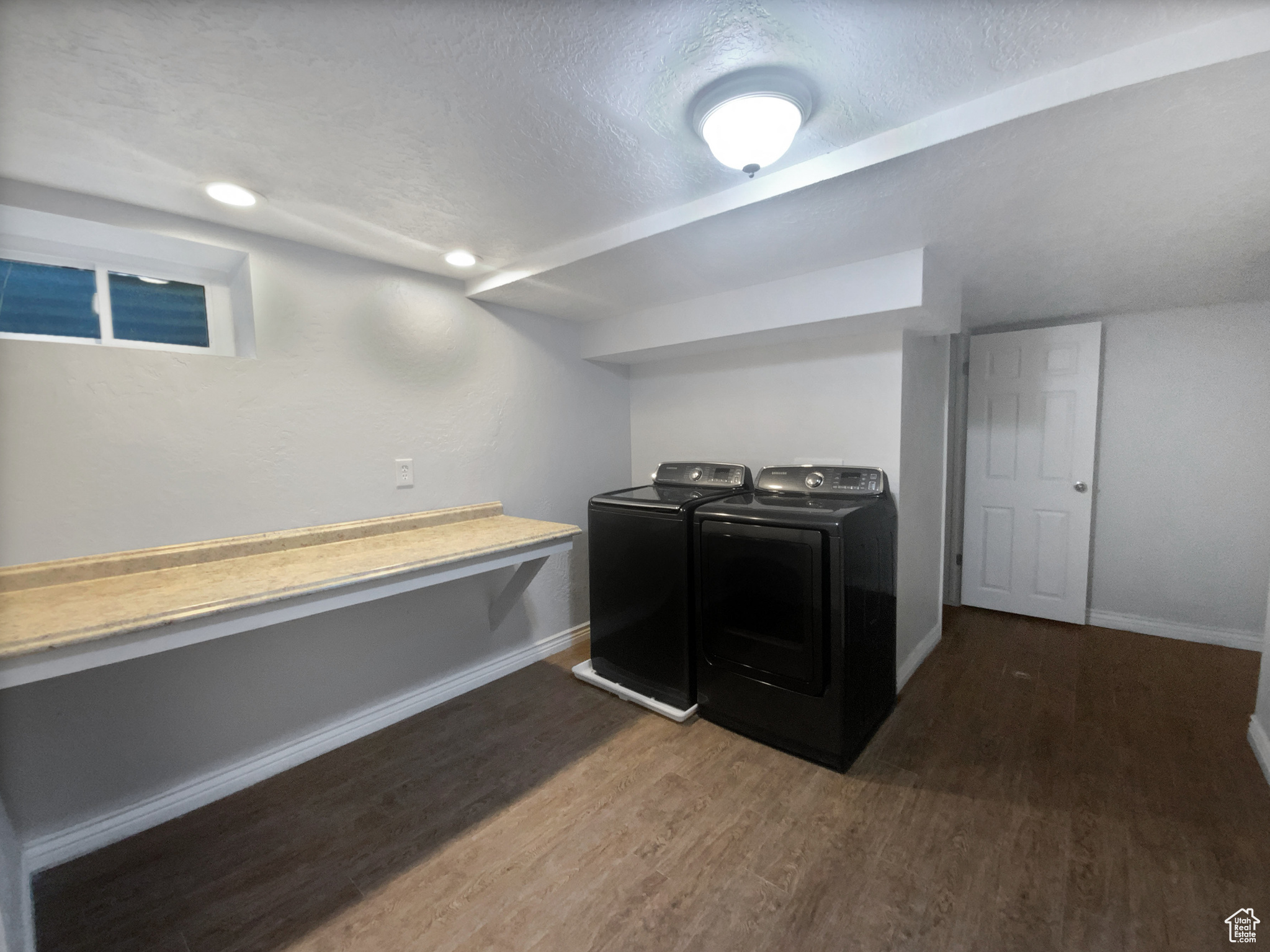 Laundry room featuring washing machine and clothes dryer, dark hardwood / wood-style flooring, and a textured ceiling