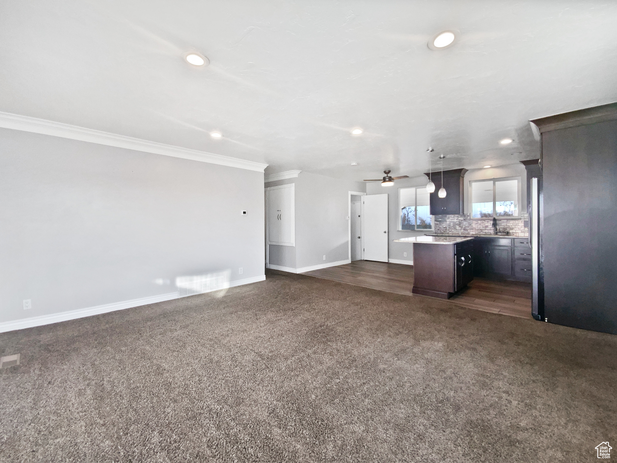 Kitchen with a center island, backsplash, sink, hanging light fixtures, and ceiling fan